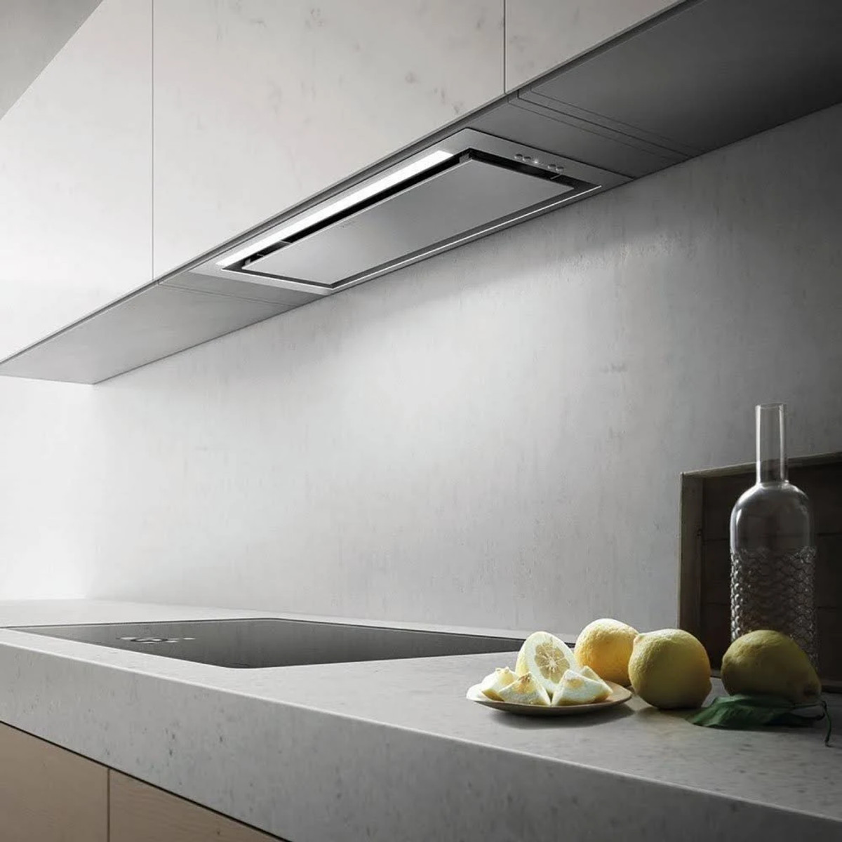 Cucina moderna con cappa integrata, piano cottura in vetro e limoni.