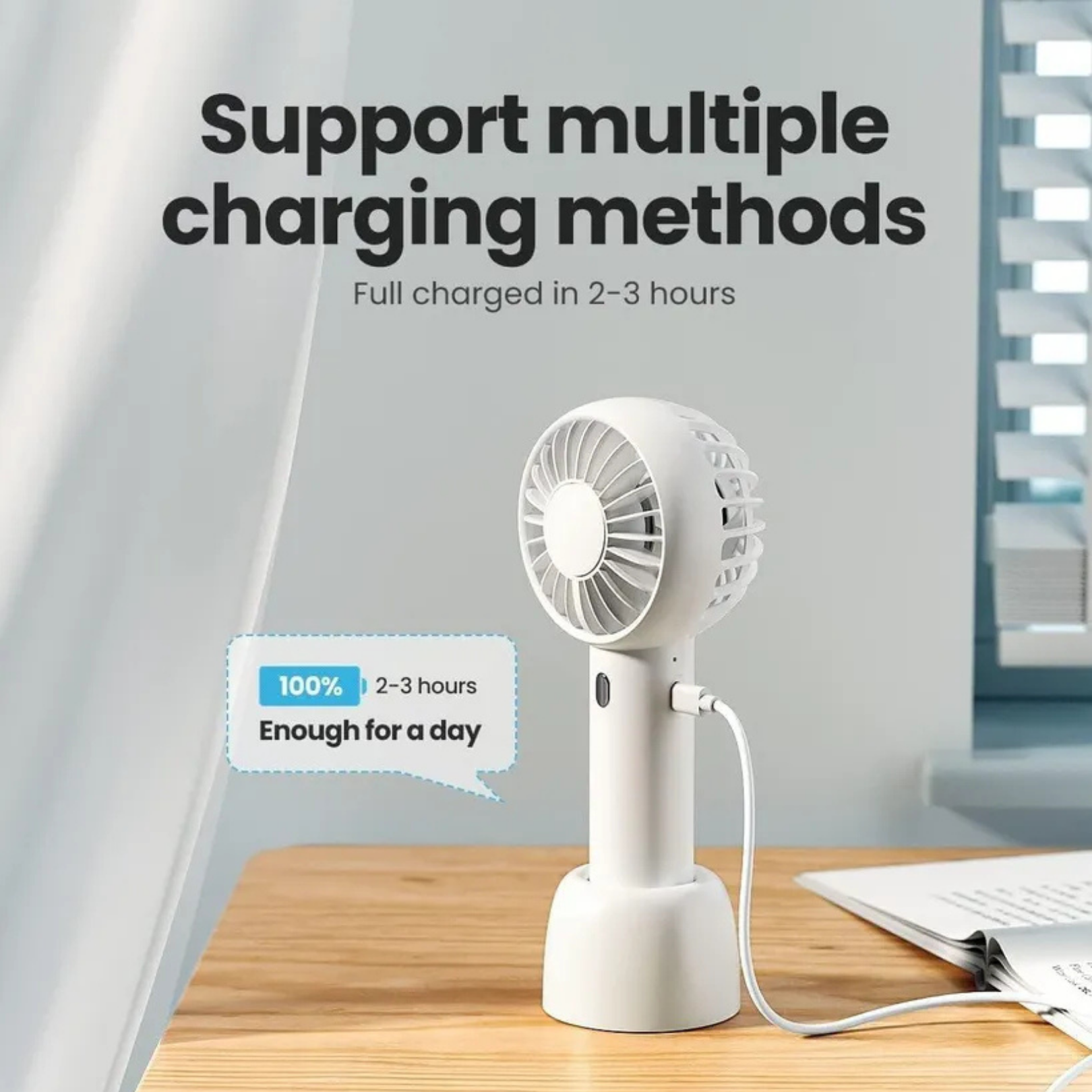 Ein weißer Handventilator mit USB-Kabel, der auf einem Holztisch steht.