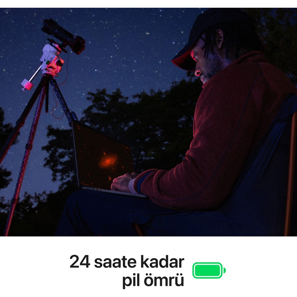 Adam yıldızlı gecede teleskop yanında dizüstü bilgisayar kullanıyor.