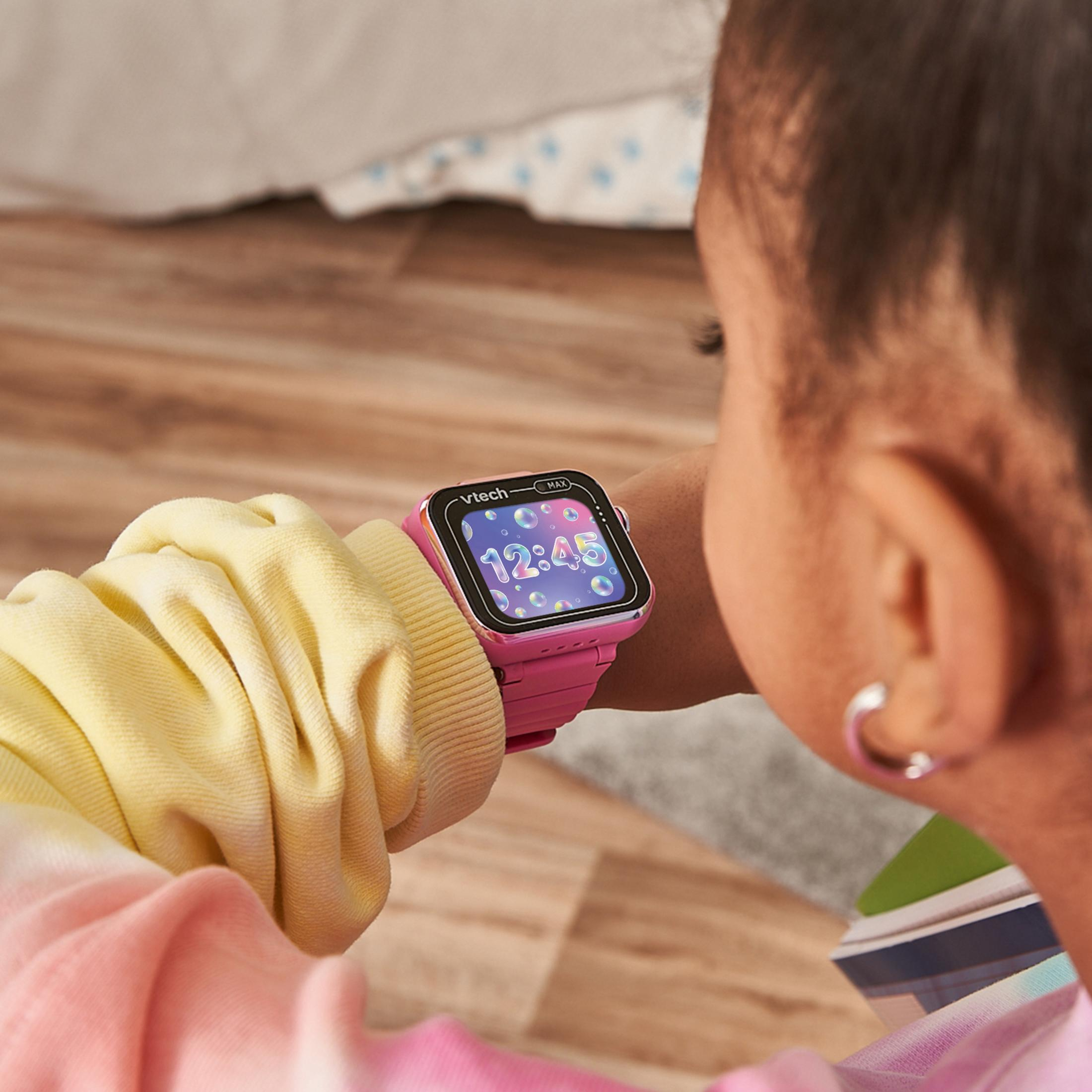 Un bambino con un orologio intelligente giocattolo Vtech rosa al polso, che mostra l'ora.