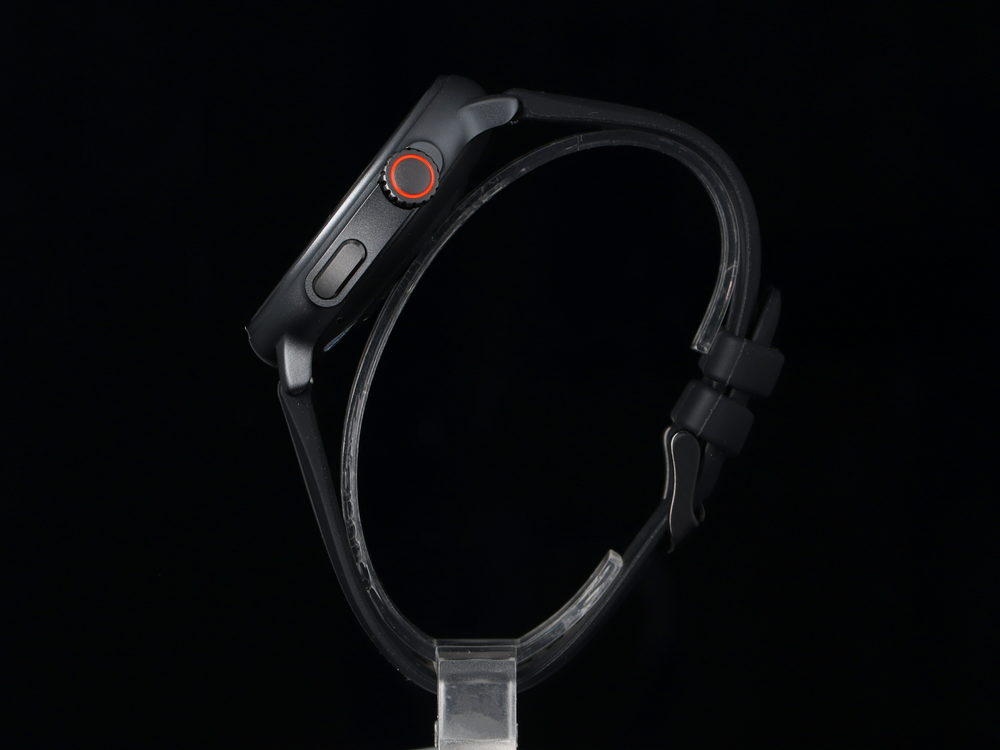 Czarny smartwatch z czerwonym przyciskiem i czarnym paskiem na czarnym tle.