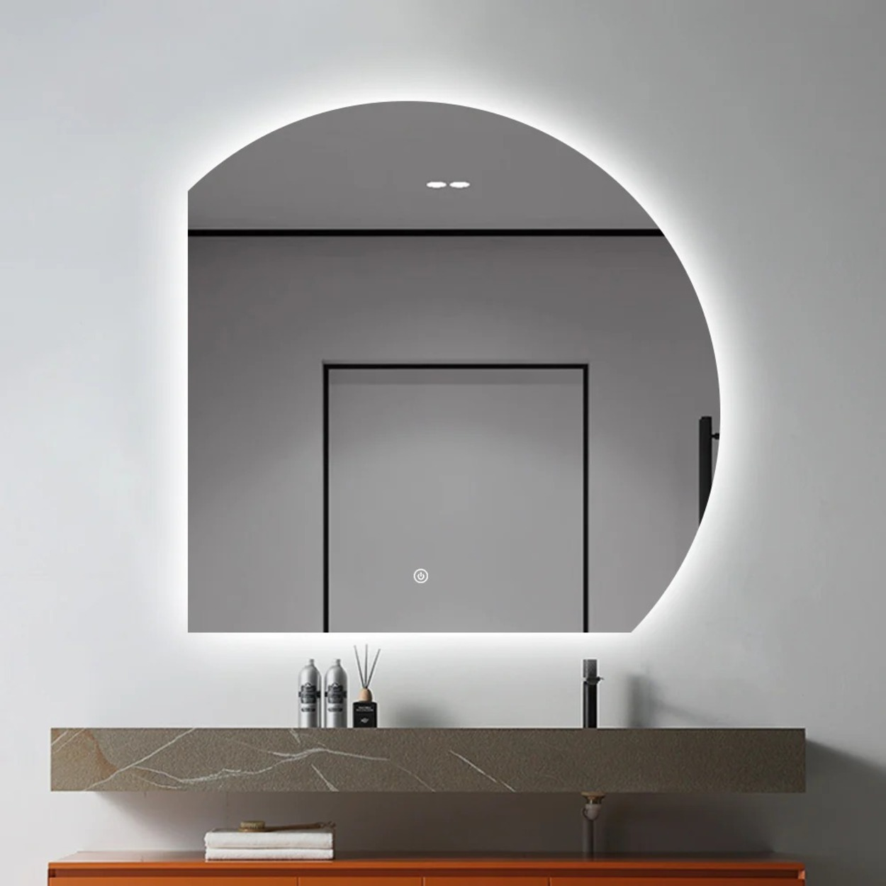 Een D-vormige spiegel met zachte LED-verlichting boven een modern badmeubel met toiletartikelen.