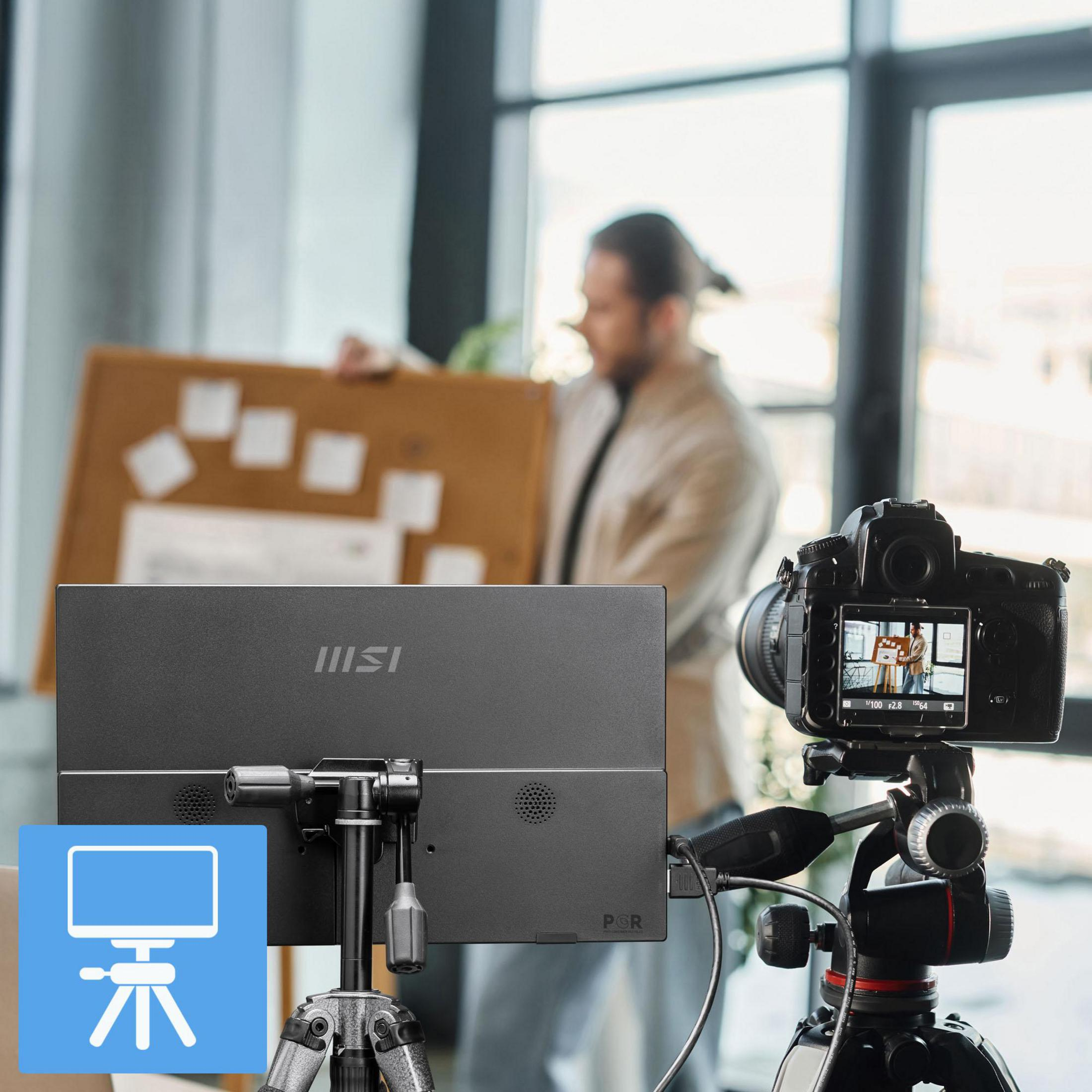 Un uomo con una lavagna viene filmato da una telecamera, un monitor è davanti.