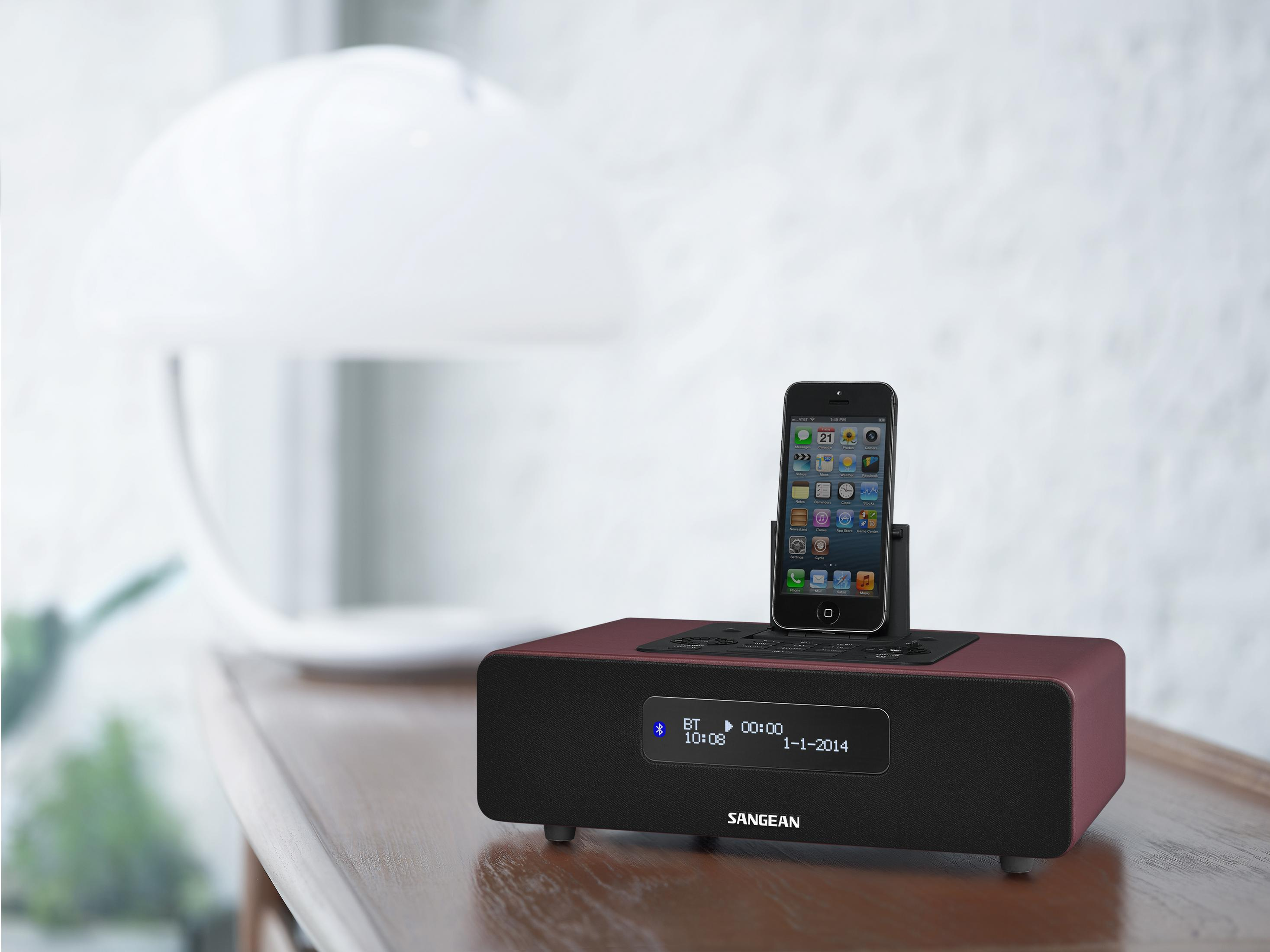 Ein schwarzes iPhone steht auf einer weinroten Dockingstation mit Display.