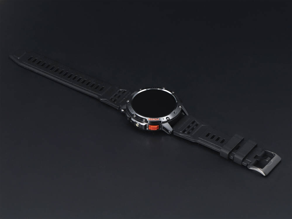 Czarny smartwatch z okrągłą tarczą i pomarańczowymi akcentami na ciemnym tle.