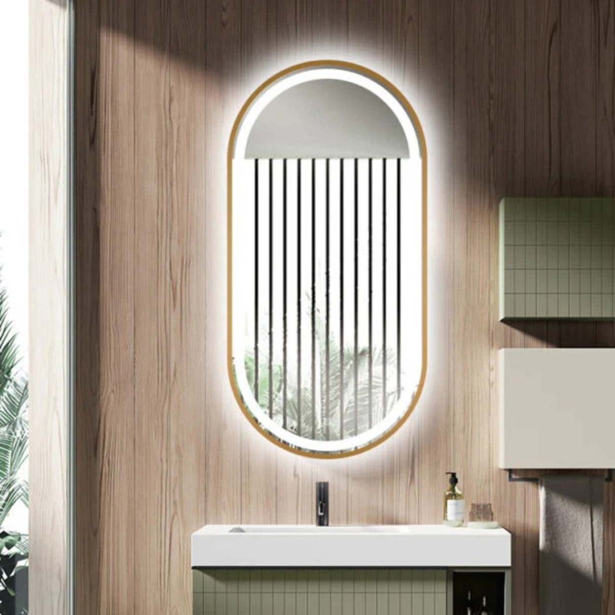 Een ovale spiegel met gouden frame en verlichting boven een wastafel.