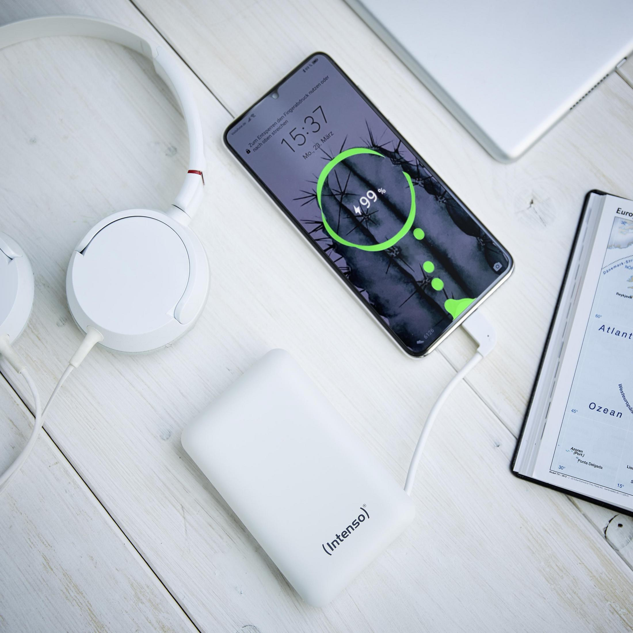 Weiße Kopfhörer, Powerbank und Handy laden auf Holzhintergrund.