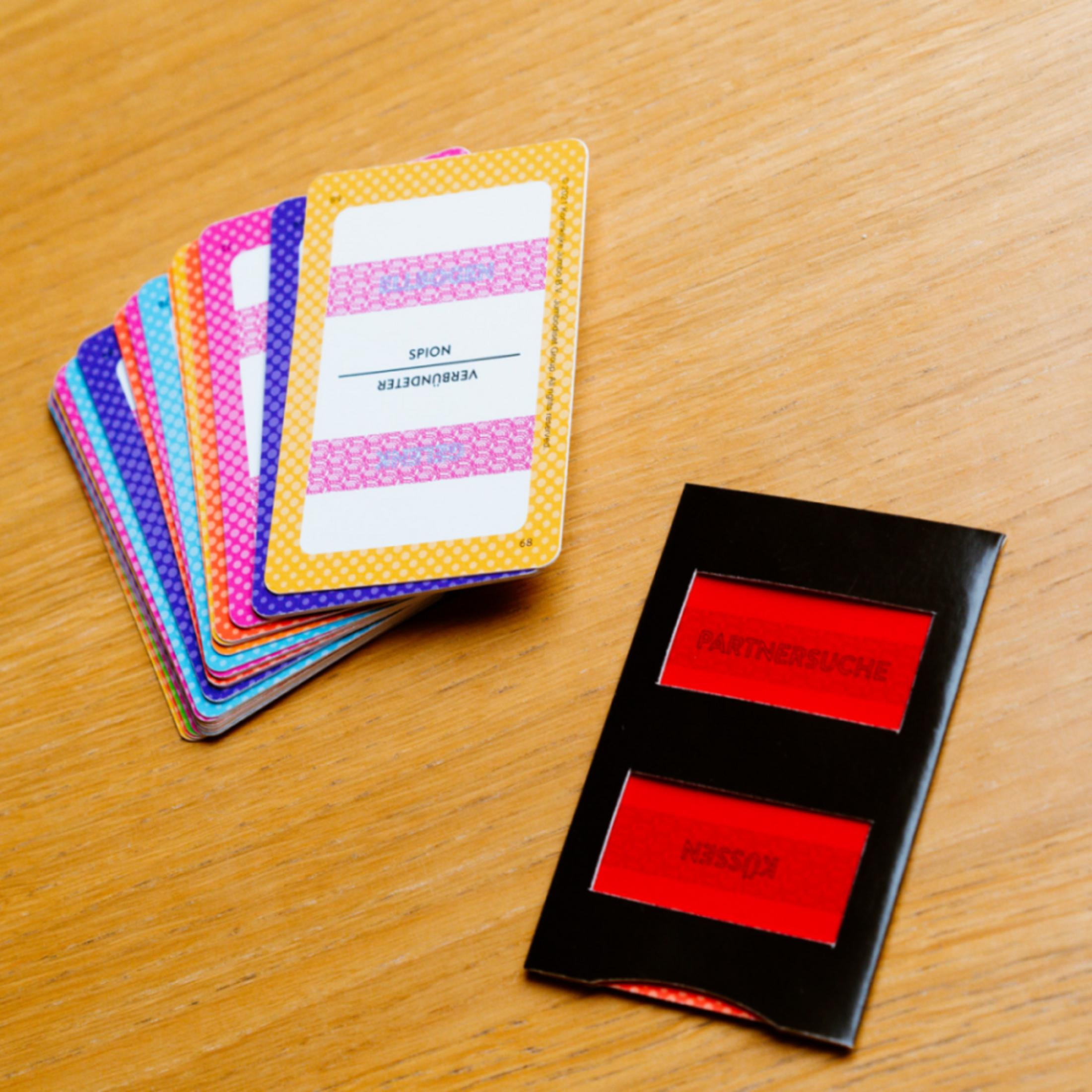 Éventail de cartes colorées et carte noire avec champs rouges sur table bois.