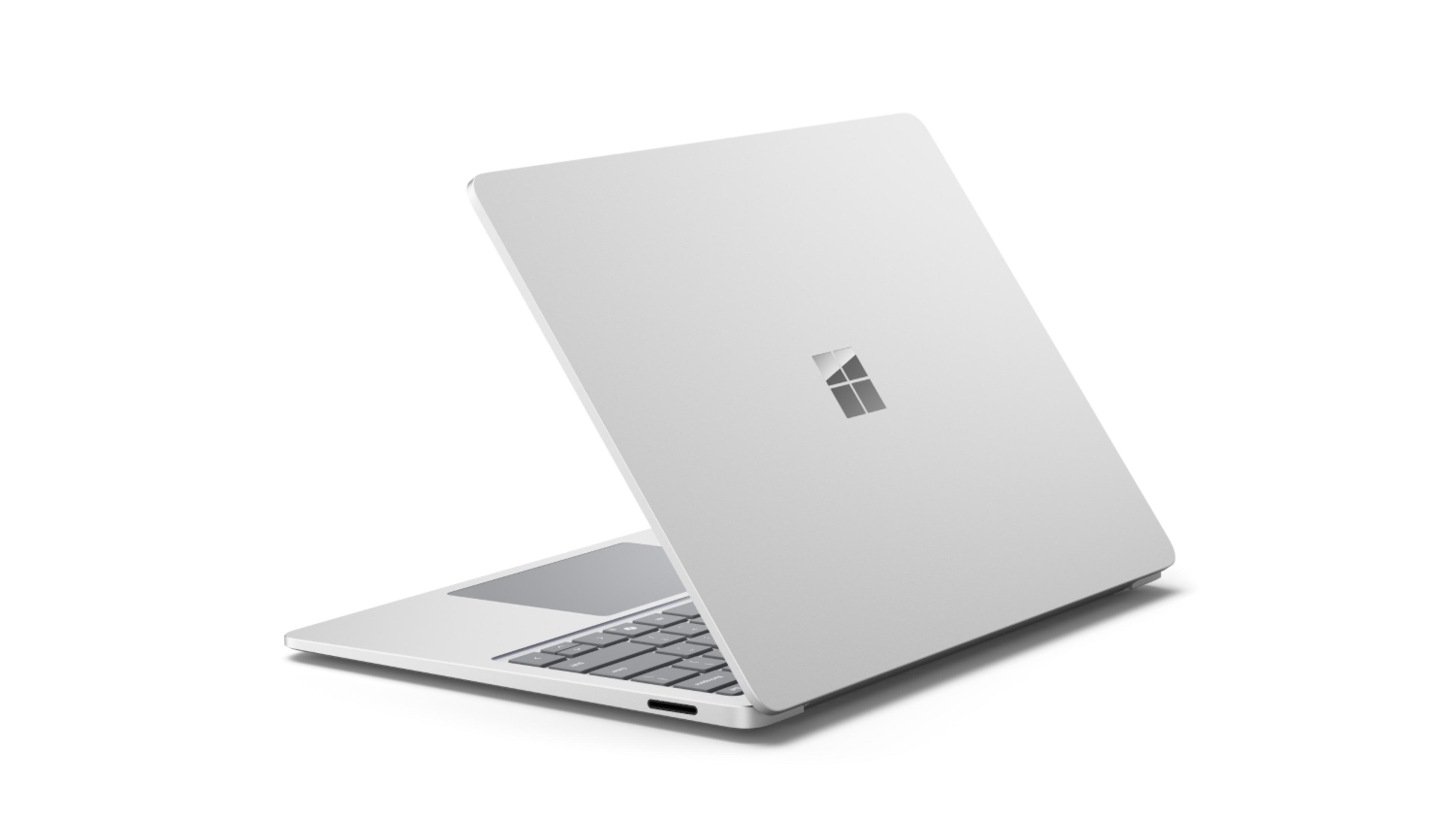 Un portátil plateado con el logo de Microsoft en la tapa cerrada, visto de lado.
