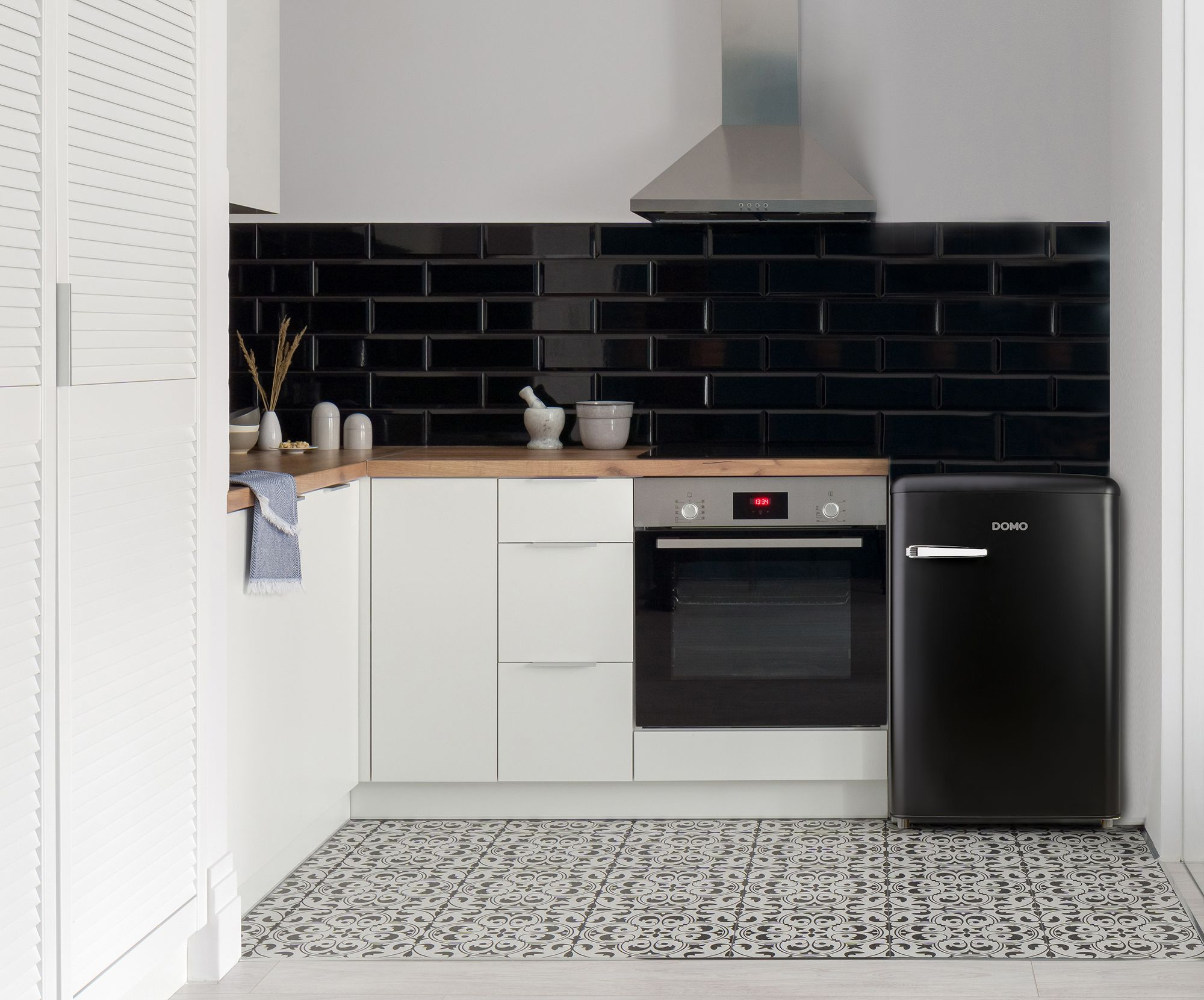 Cuisine moderne avec crédence en carreaux métro noirs, armoires blanches, four et réfrigérateur rétro noir.