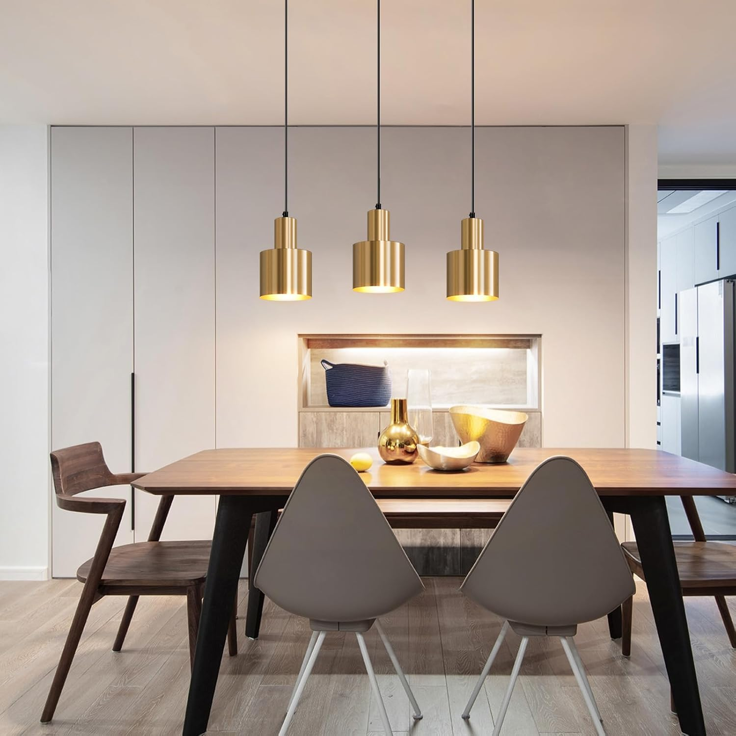 Ein Esstisch mit Stühlen unter drei goldenen Hängeleuchten in einem modernen Esszimmer.
