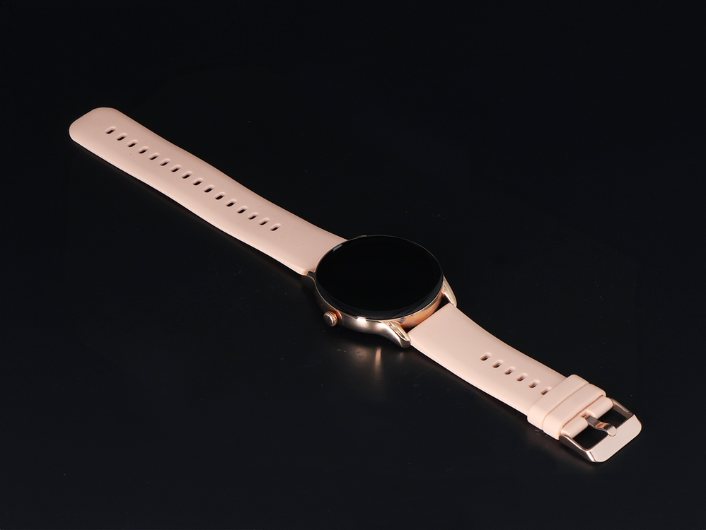 Smartwatch w kolorze różowego złota z jasnoróżową bransoletą na czarnym tle.