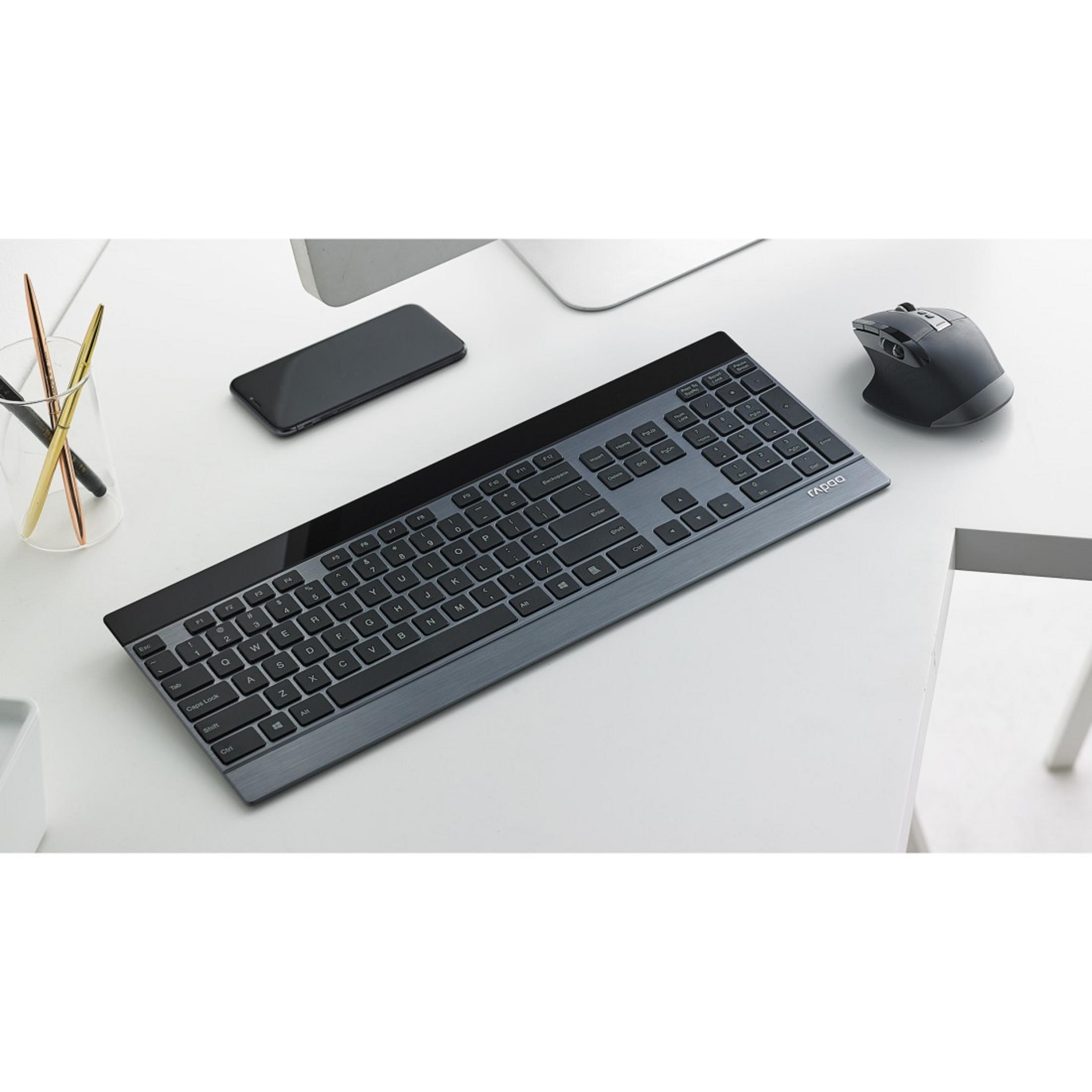 Drahtlose Tastatur und Maus auf einem weißen Schreibtisch mit Stiften und Telefon.