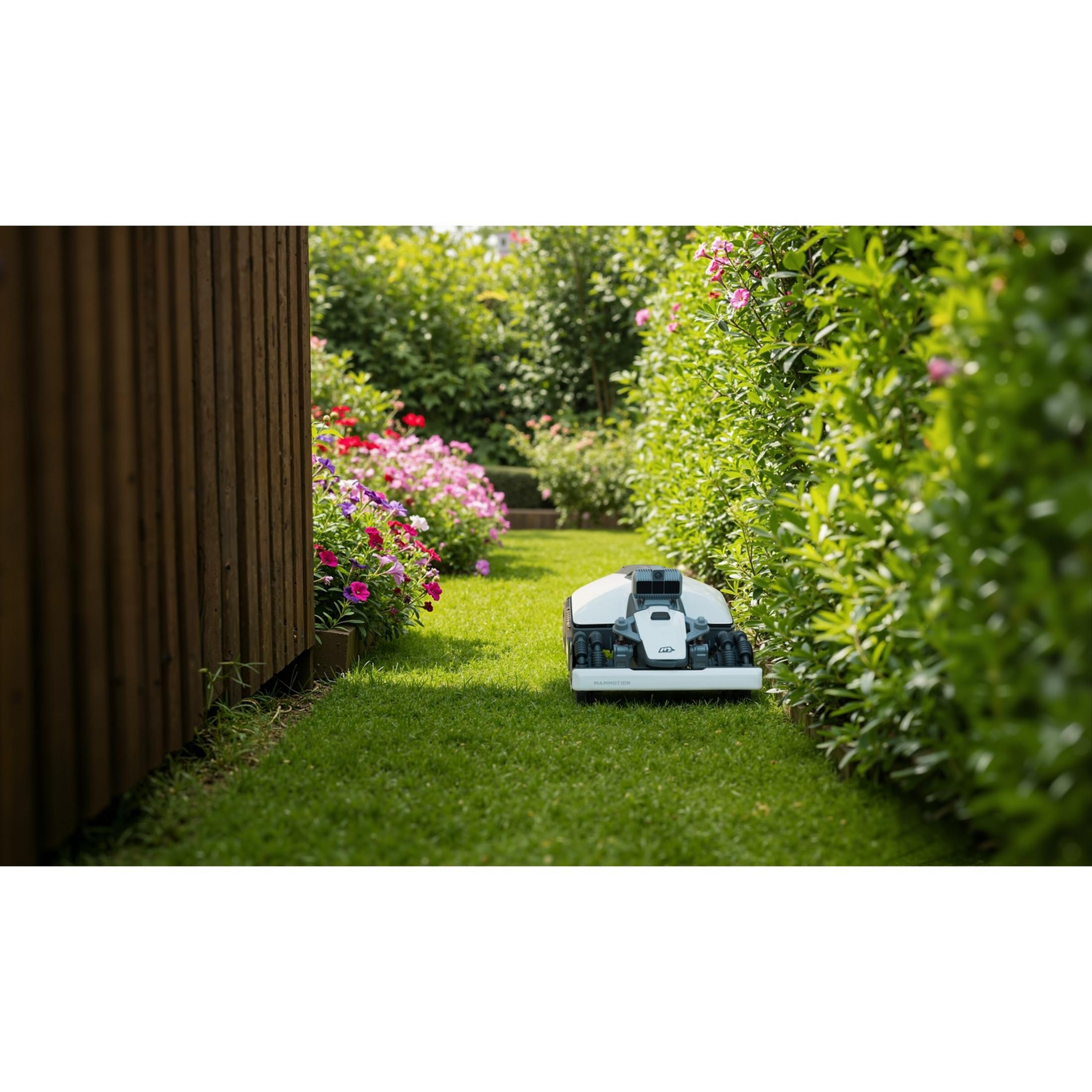 Un robot cortacésped blanco está sobre césped verde junto a un parterre.