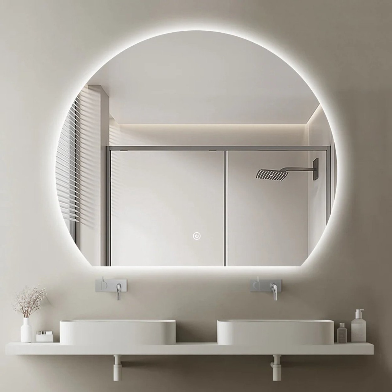 Moderne badkamer met verlicht rond spiegel, dubbele wastafels en douche zichtbaar.