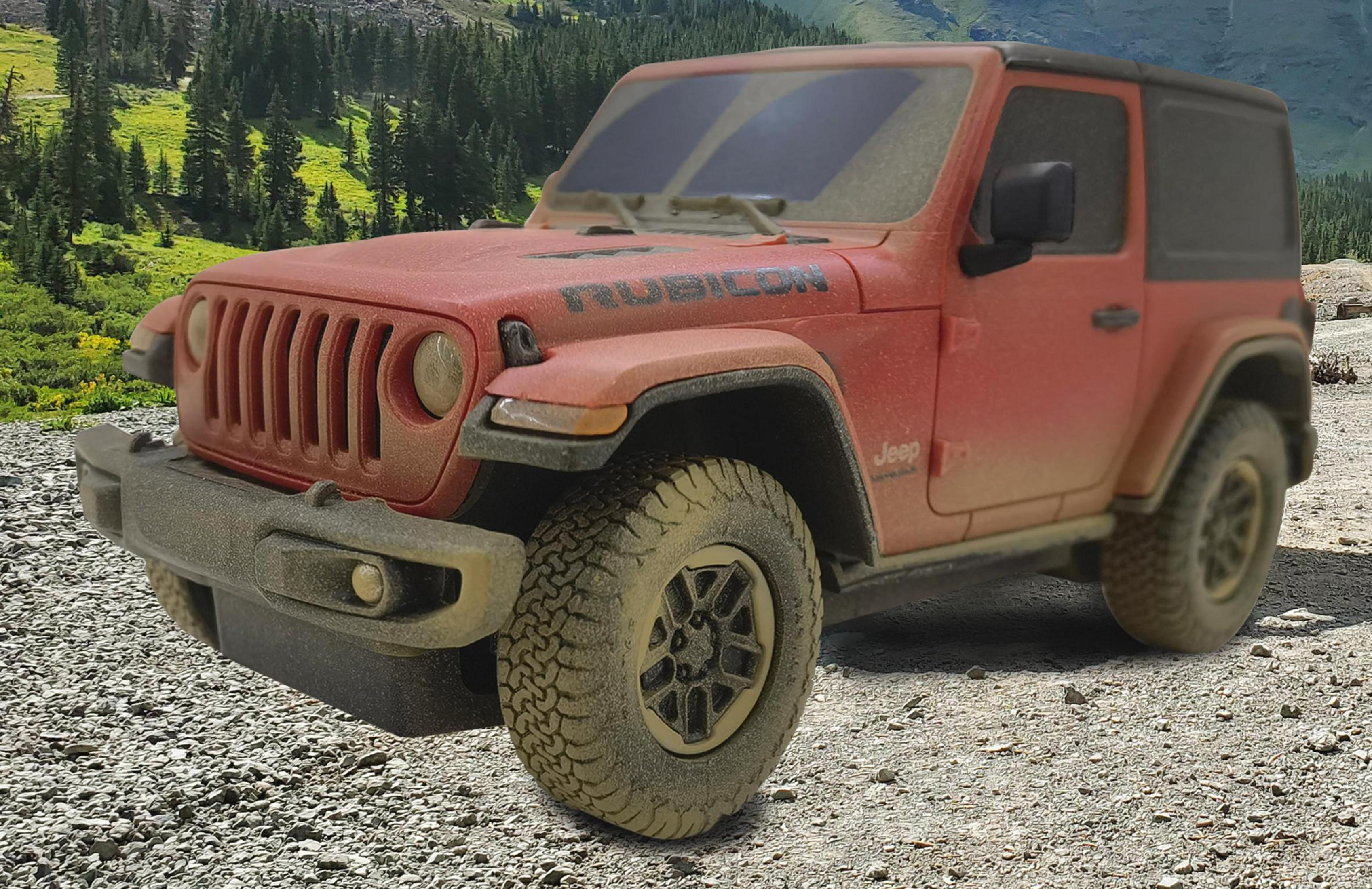 Ein roter Jeep Rubicon steht auf einer Schotterstraße mit Bäumen im Hintergrund.