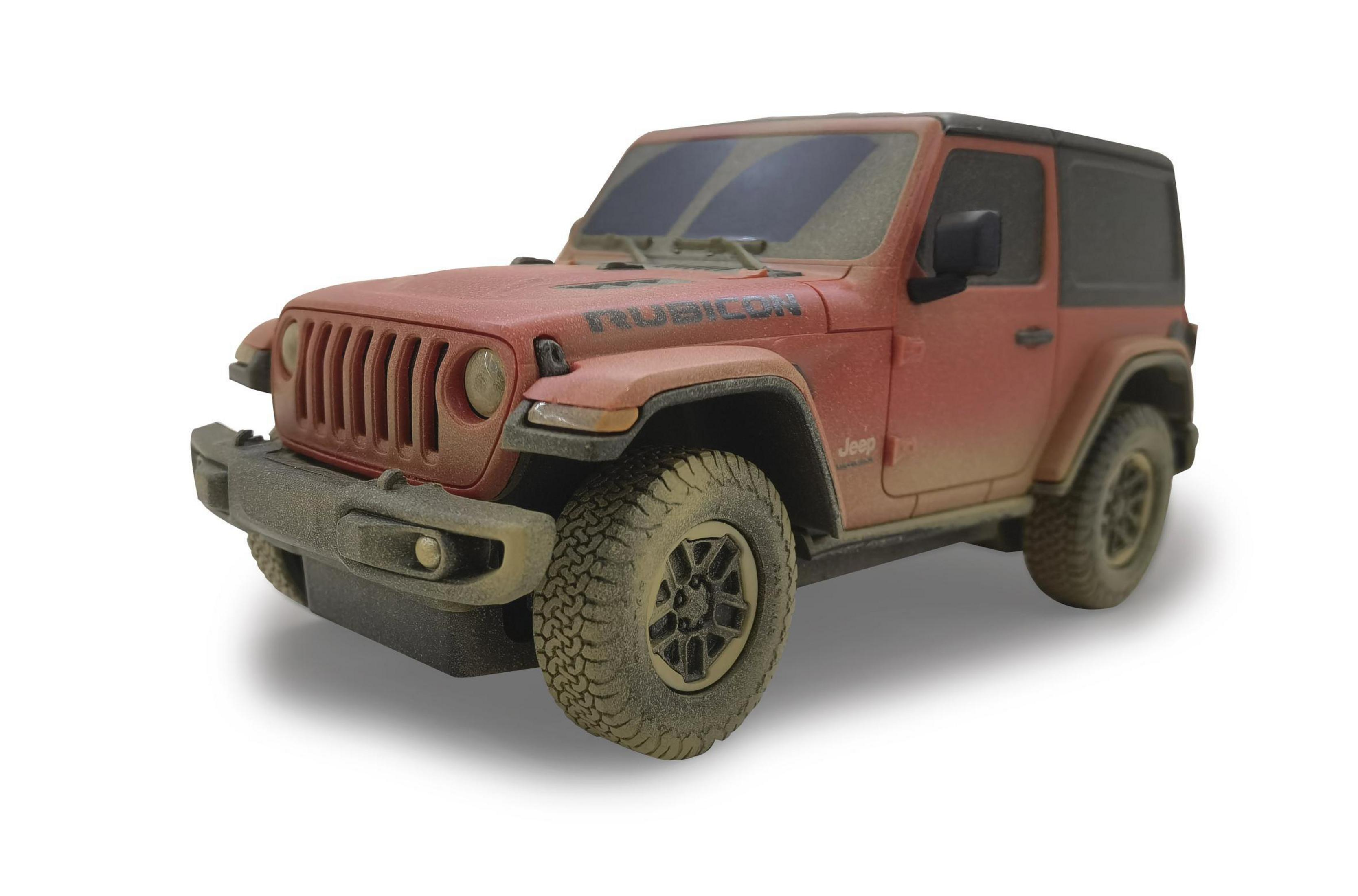 Ein schlammbedeckter, roter Jeep Wrangler Rubicon mit schwarzen Akzenten steht vor einem weißen Hintergrund.