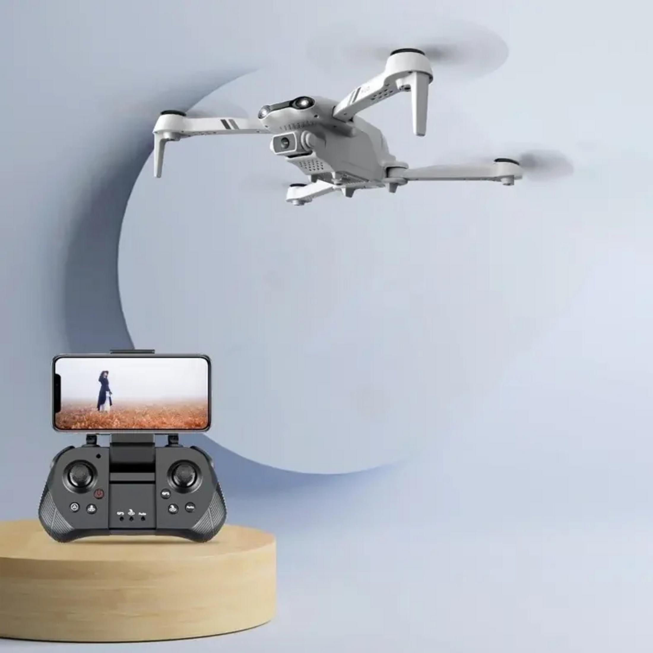 Biały dron unosi się nad pilotem z podłączonym smartfonem.
