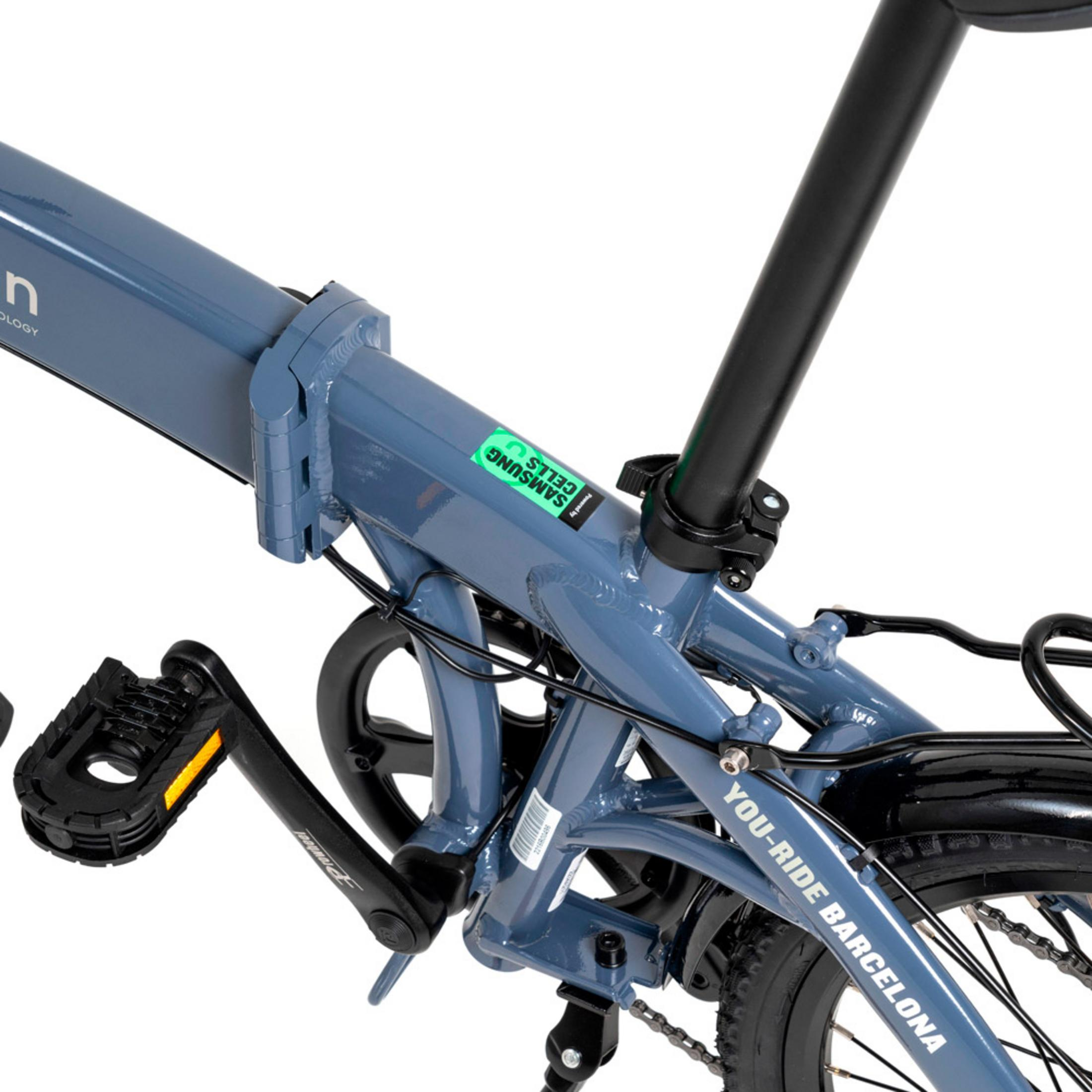 Ein blauer Klappradrahmen mit Pedalen, Kette und Aufkleber 'Samsung Cells'.