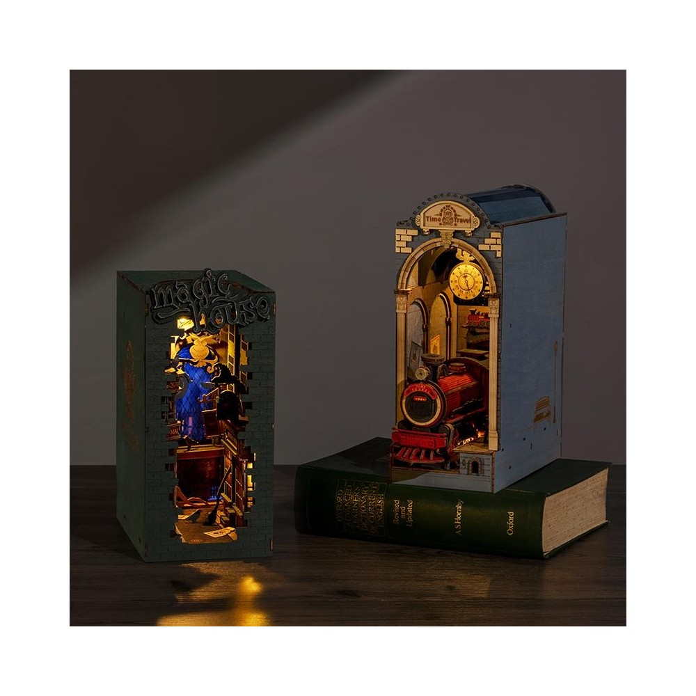 İki aydınlatılmış diorama: bir ev ve bir tren, bir kitap üzerinde.