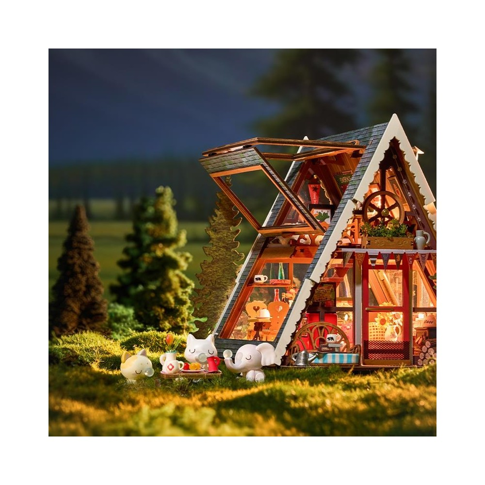 Casa miniatura con figuras en el césped al anochecer.