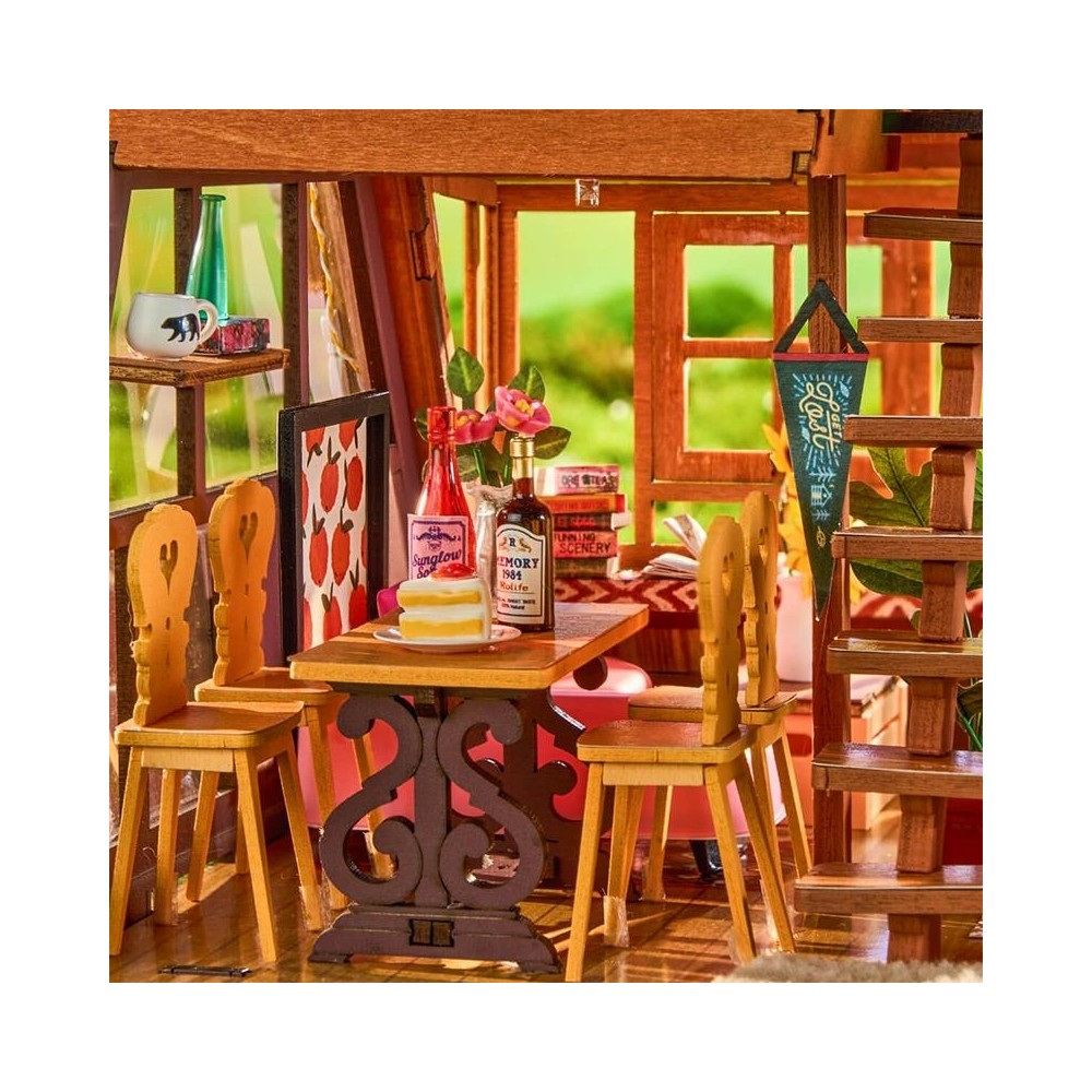 Área de comedor en miniatura con mesa de madera, sillas, pastel, botellas y libros.