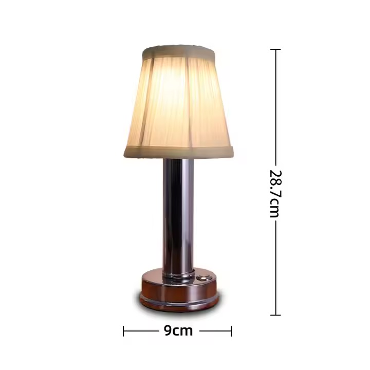 Eine kleine Tischlampe mit weißem Faltenlampenschirm und Chromfuß.