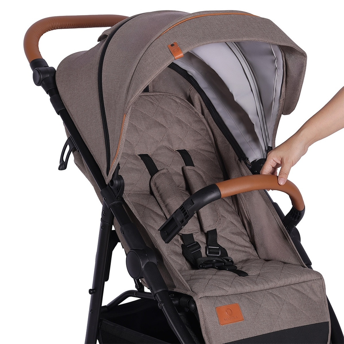 Brauner Kinderwagen mit gepolstertem Sitz und einem Griff, den eine Hand hält.