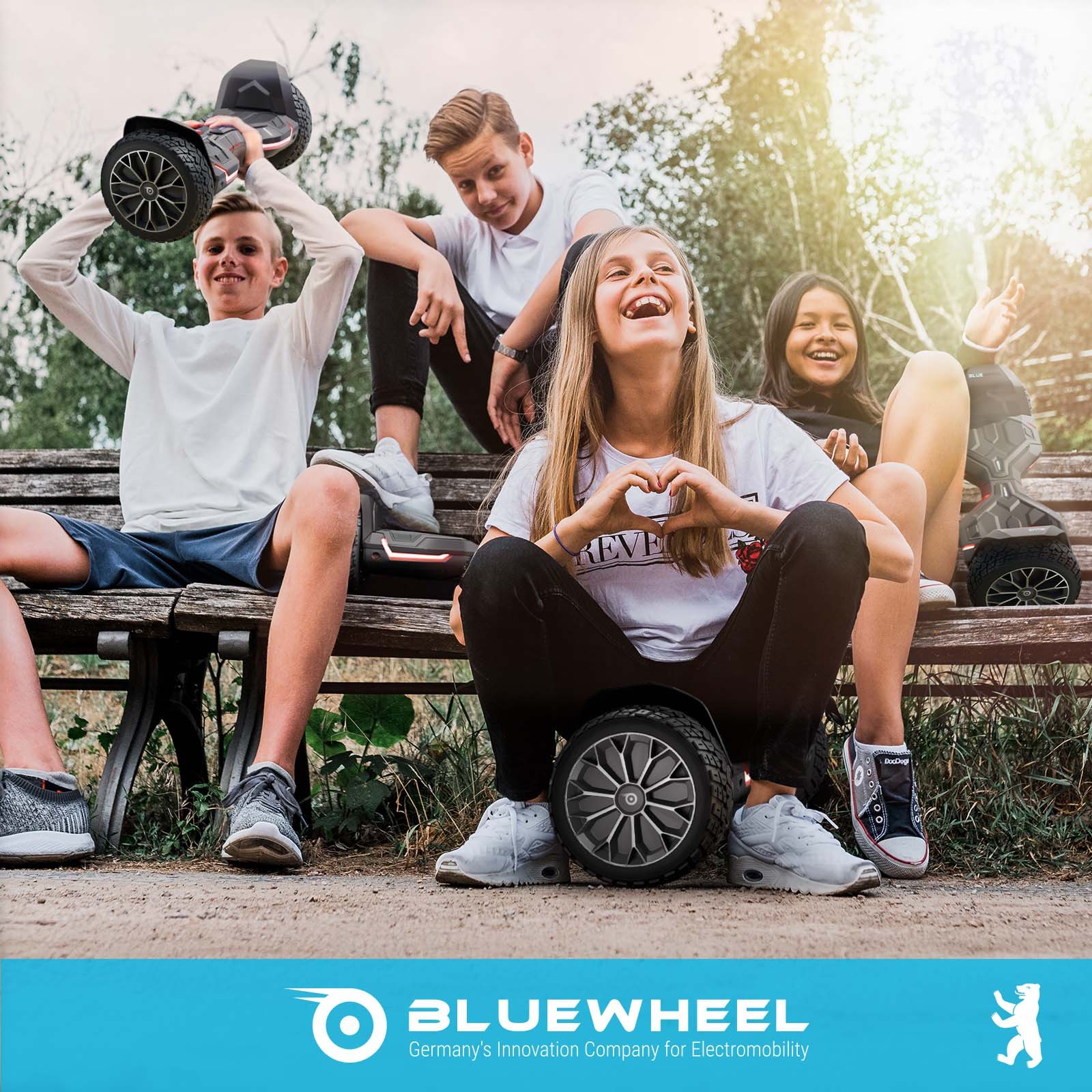 Fünf lachende Jugendliche sitzen auf einer Bank mit Hoverboards.