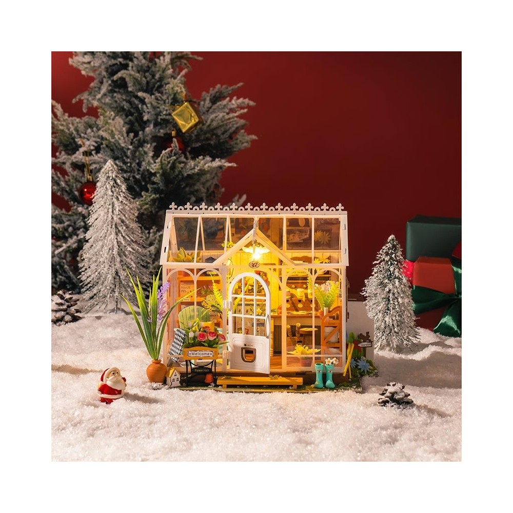 Karda bir Noel Baba, ağaçlar ve hediyelerle minyatür bir sera.