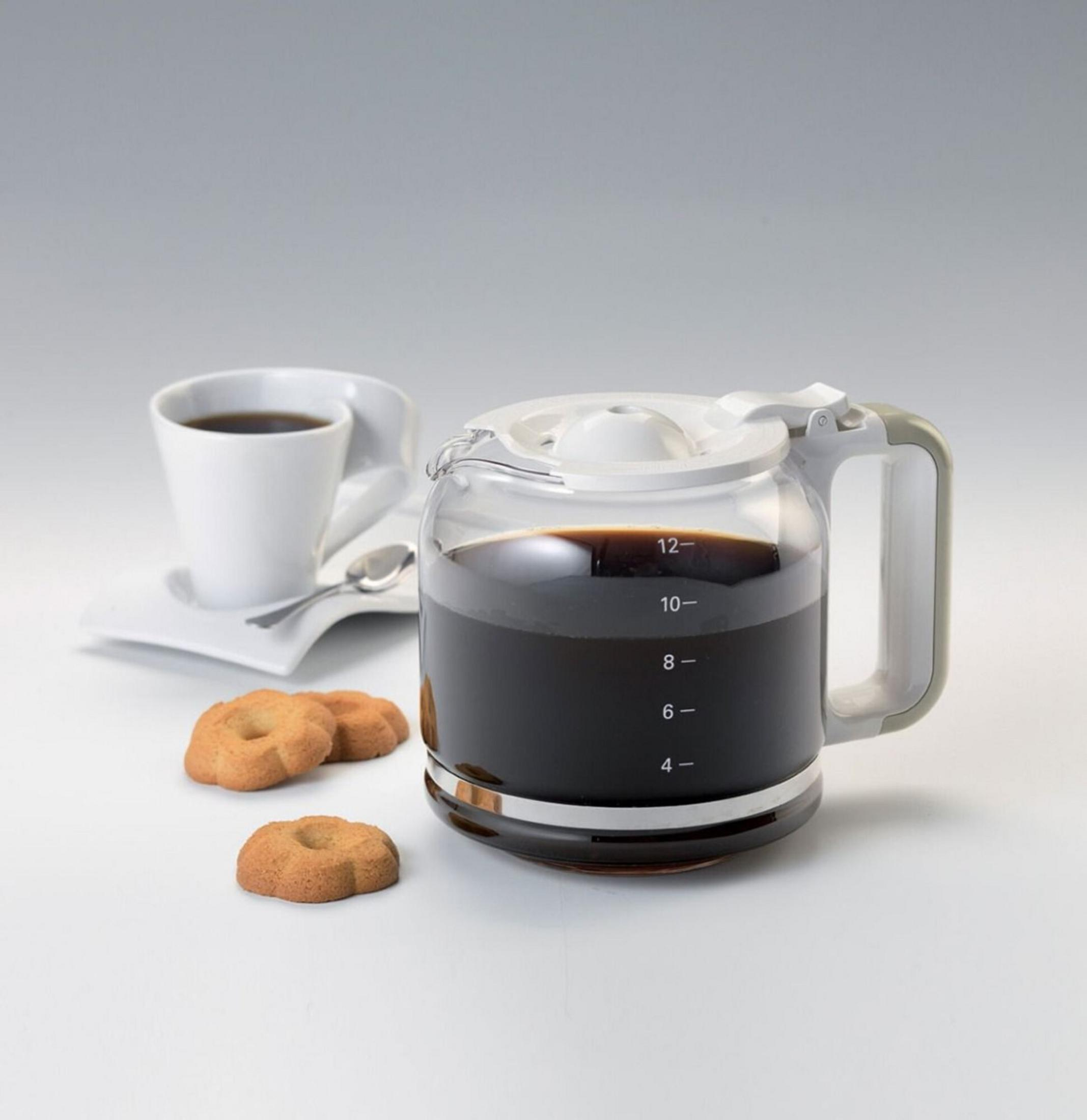 Eine gläserne Kaffeekanne mit dunklem Kaffee steht neben einer weißen Tasse Kaffee und zwei Keksen.
