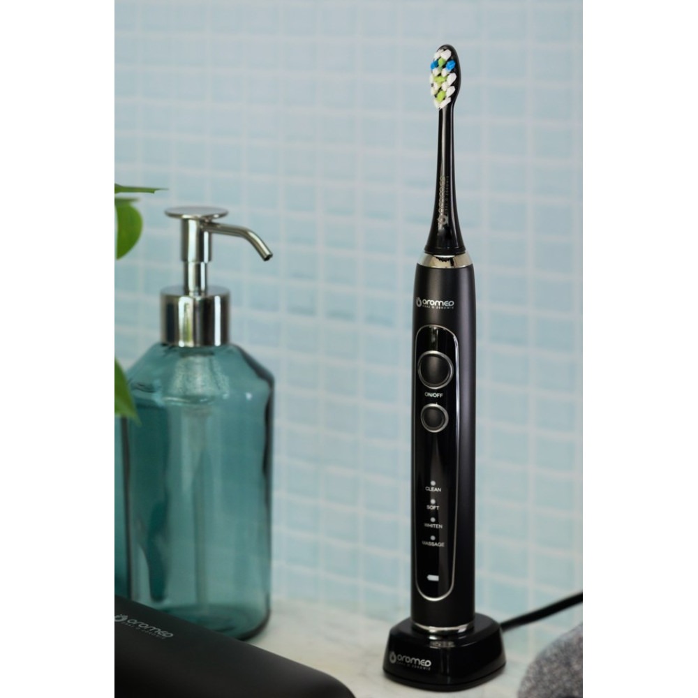 Spazzolino elettrico nero con setole colorate su un supporto accanto a un dispenser di sapone blu.