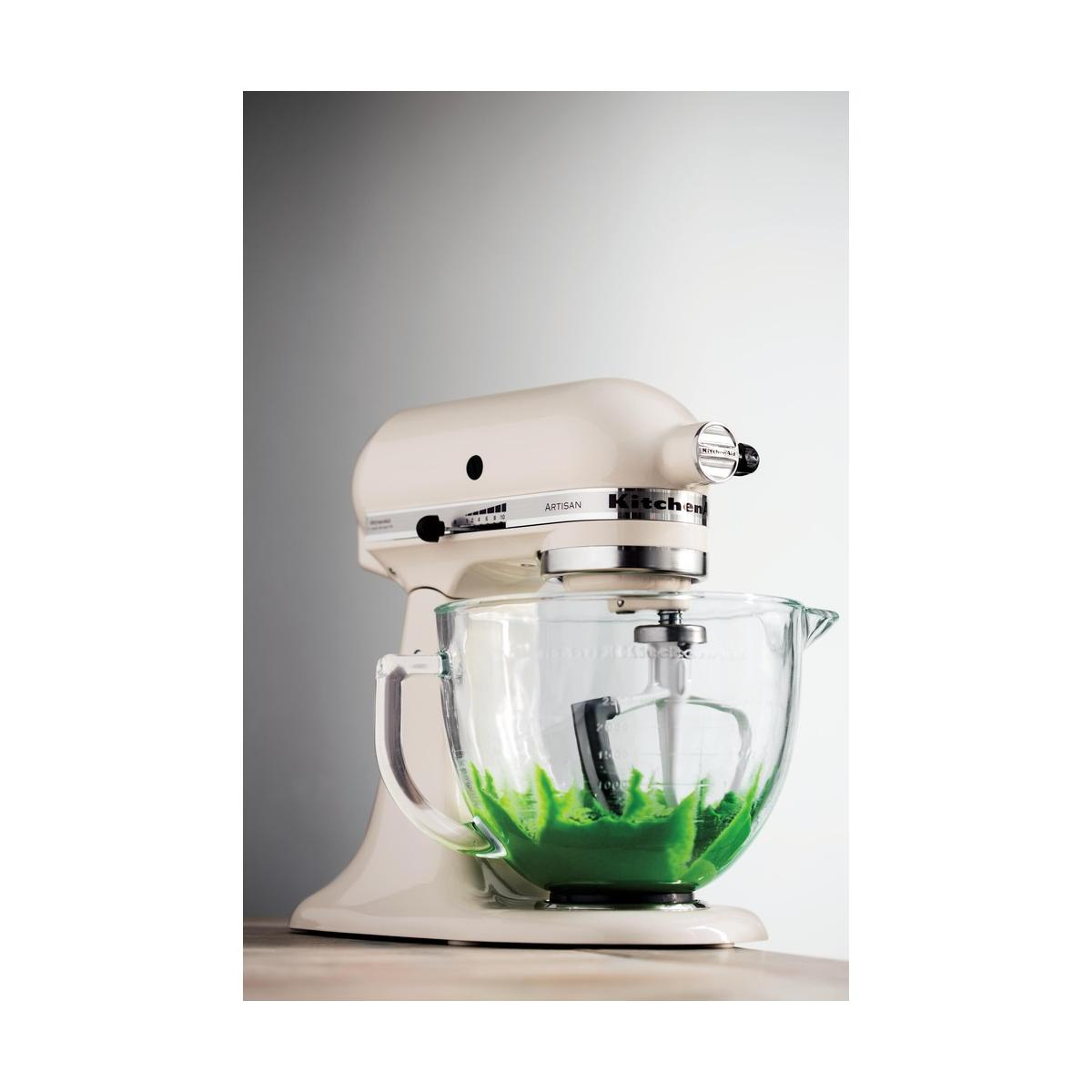 Een crèmekleurige keukenmixer met een glazen kom met groen beslag.