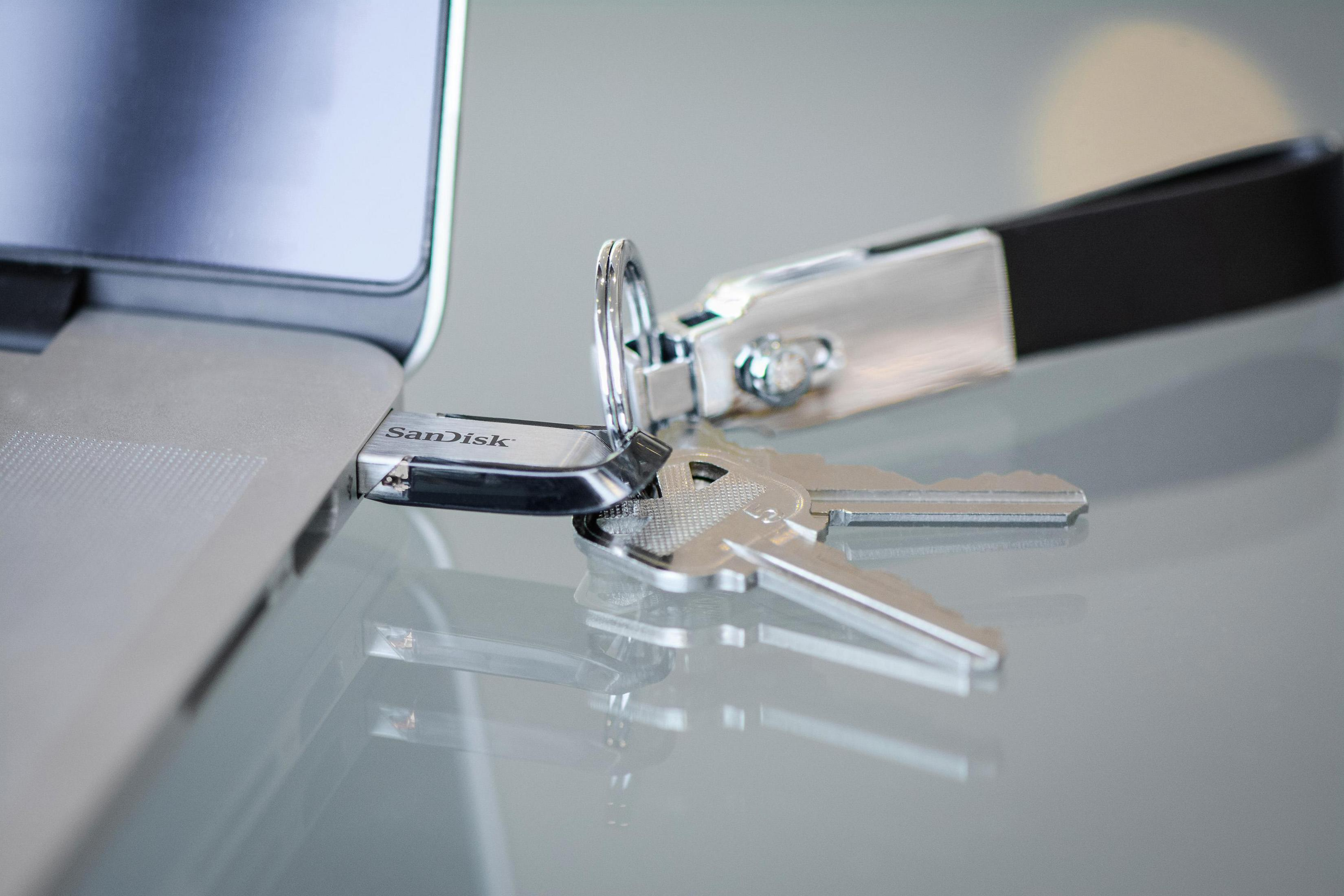 Un'unità USB inserita in un laptop, con chiavi accanto.