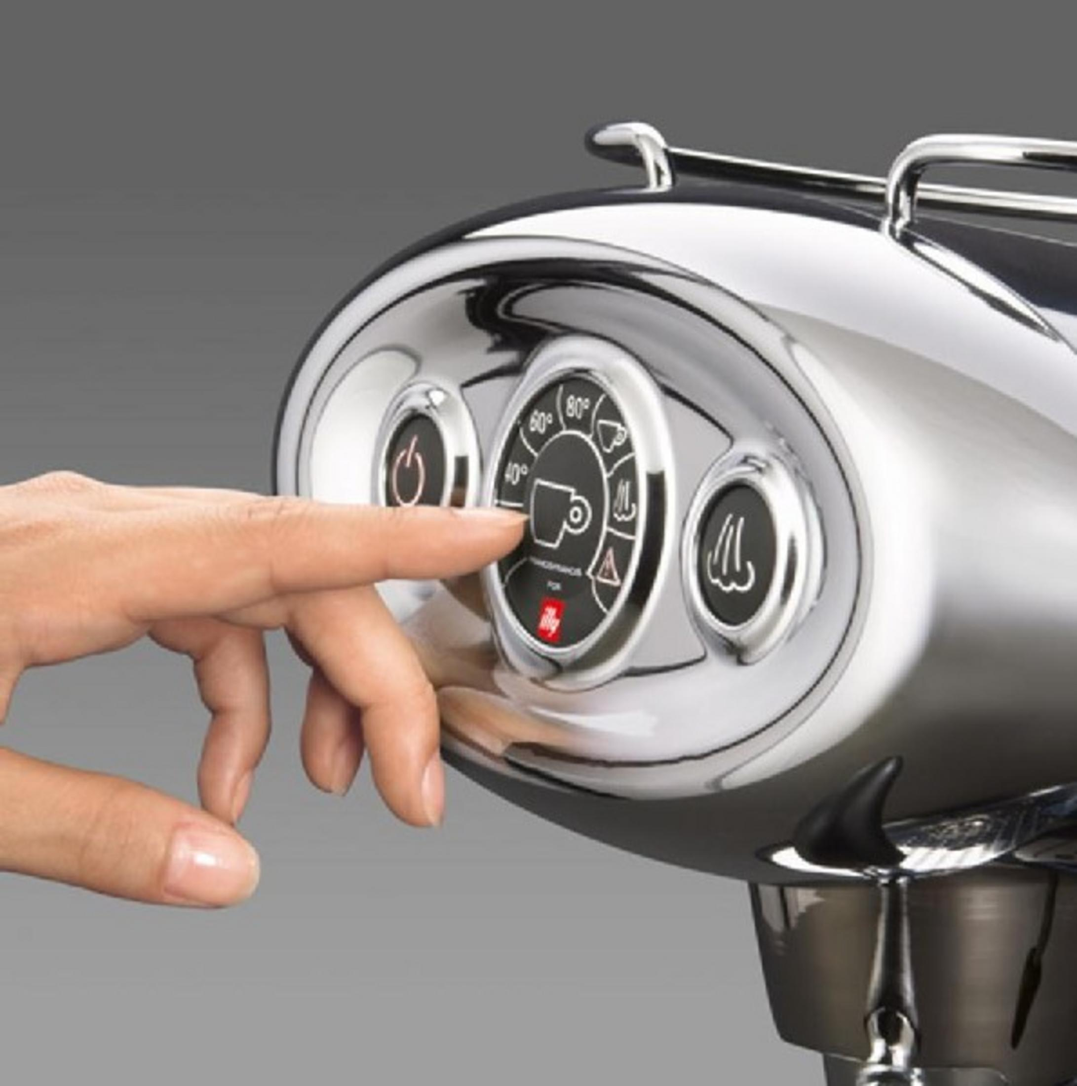 Una mano preme il pannello di controllo di una macchina espresso cromata con icona.
