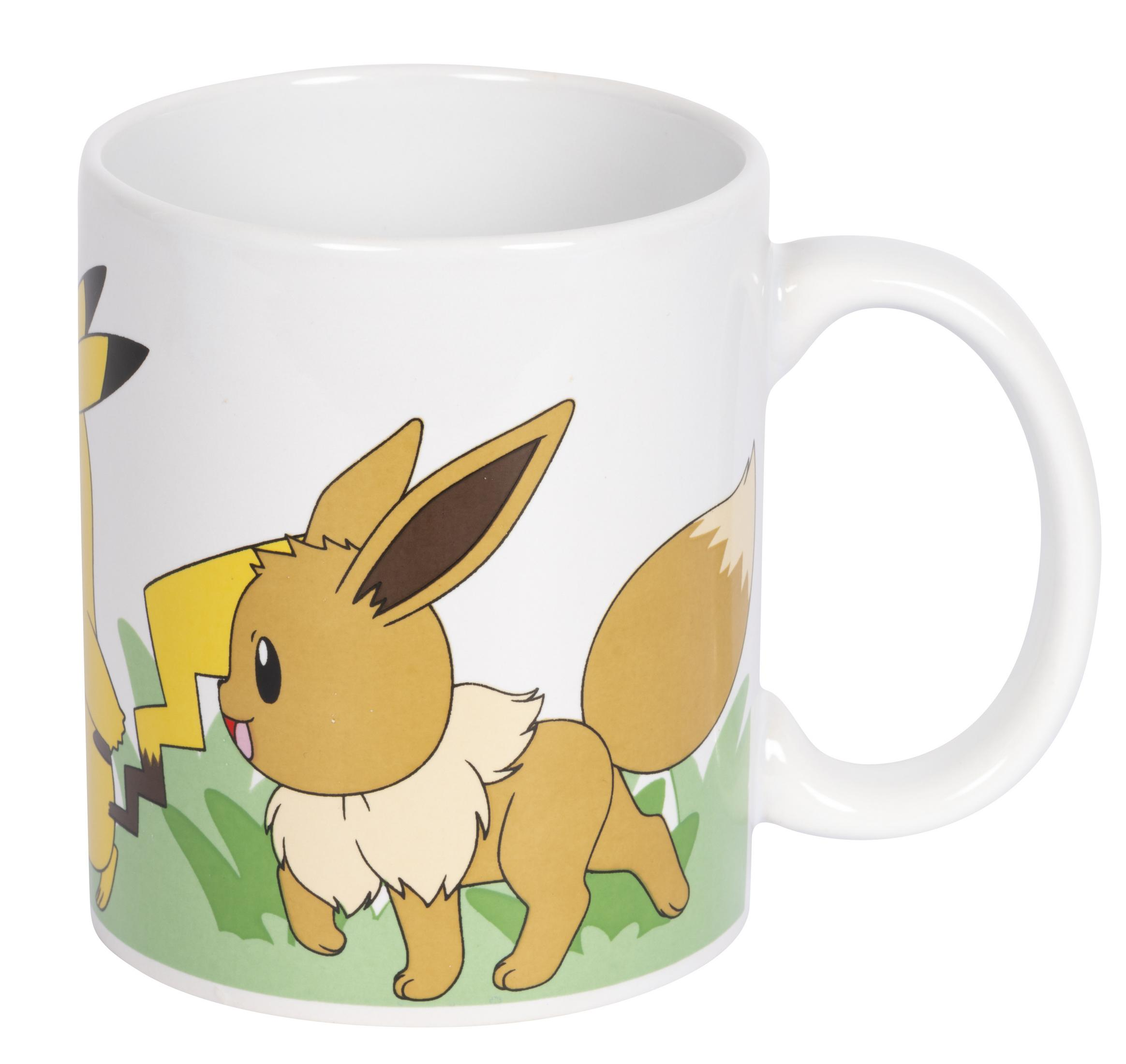 Eine weiße Tasse mit Evoli und Pikachu-Aufdruck auf grünem Gras.
