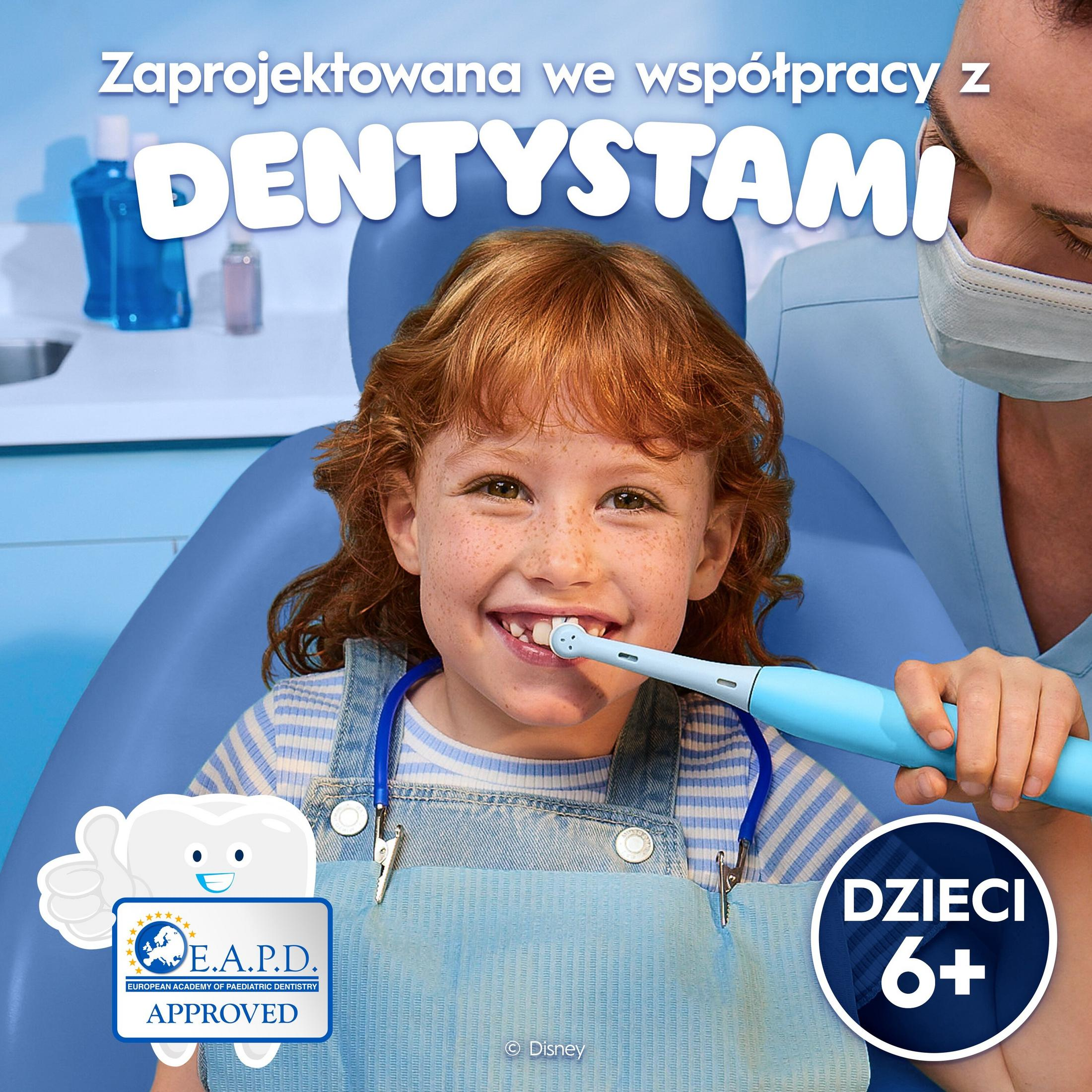 Una niña se cepilla los dientes con un cepillo eléctrico, junto a un dentista.