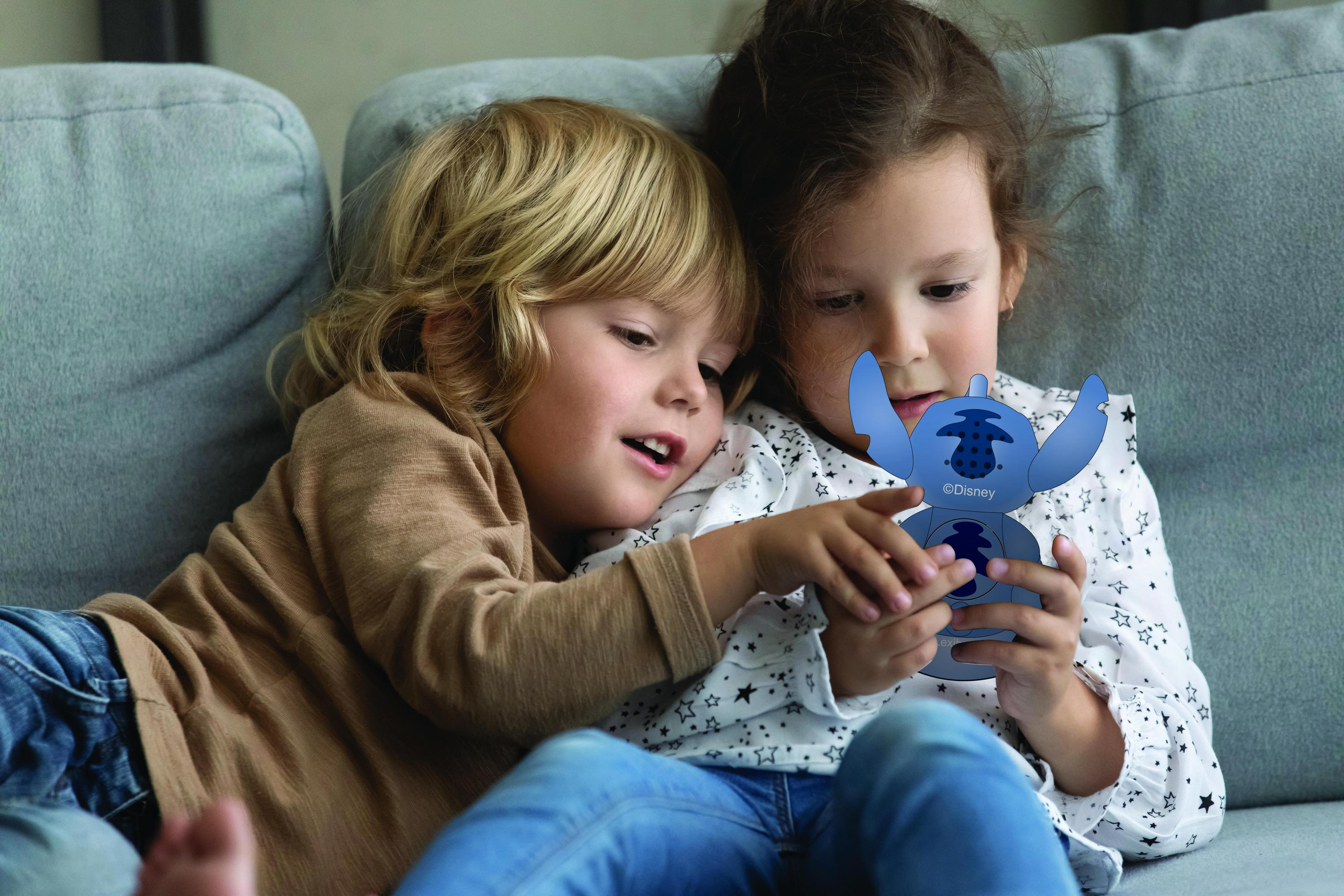 Due bambini si stringono tenendo un giocattolo blu di Stitch.