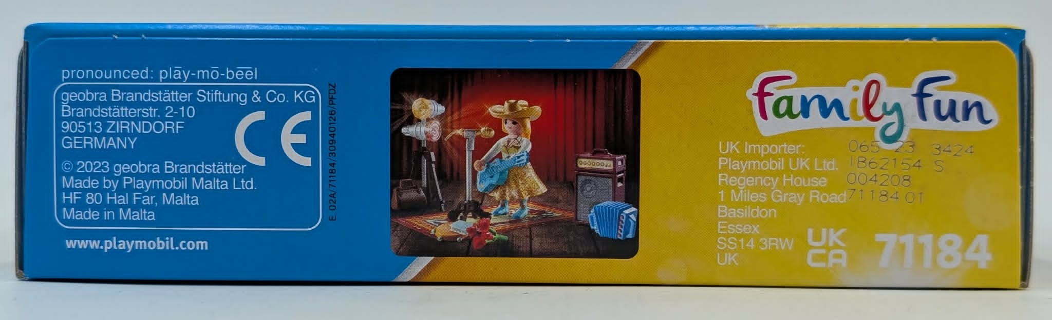Figurka Playmobil gra na gitarze na scenie z mikrofonem i akordeonem.