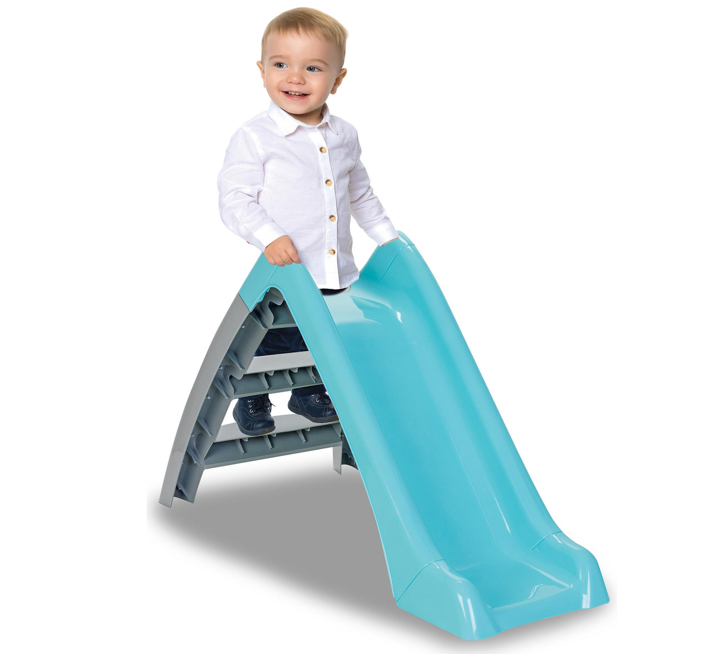 Un bambino piccolo con camicia bianca è su uno scivolo turchese.