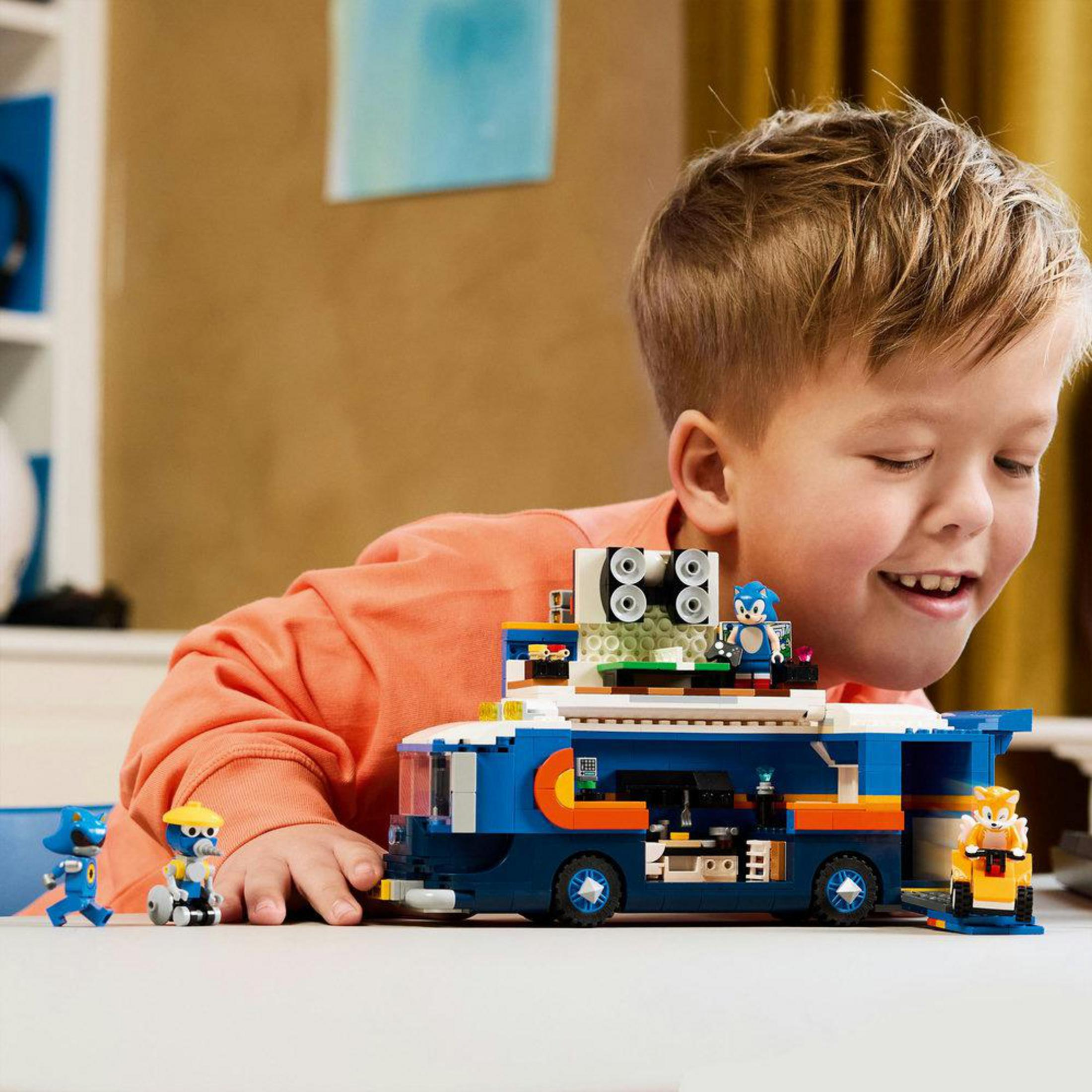 Un ragazzo gioca con un autobus Lego blu e personaggi di Sonic.