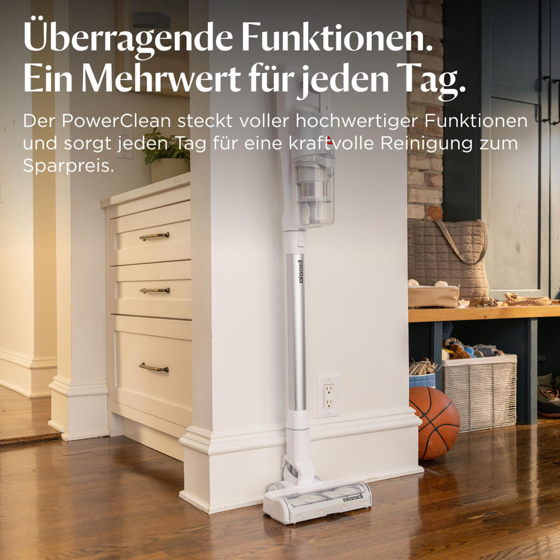 Ein weißer Akku-Staubsauger steht neben einer Kommode und einem Basketball.