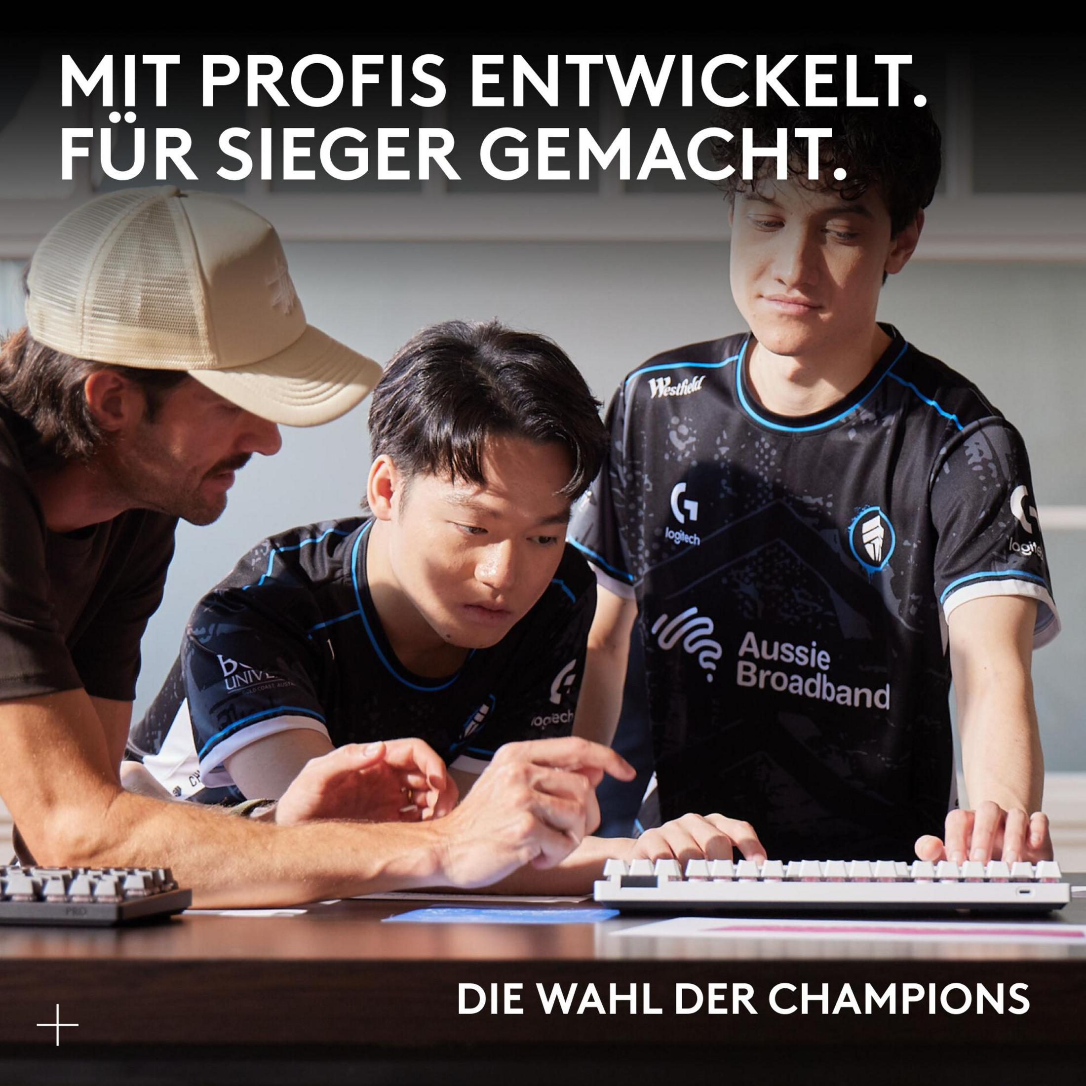 Tre uomini con maglie da e-sport guardano una tastiera, uno la indica.