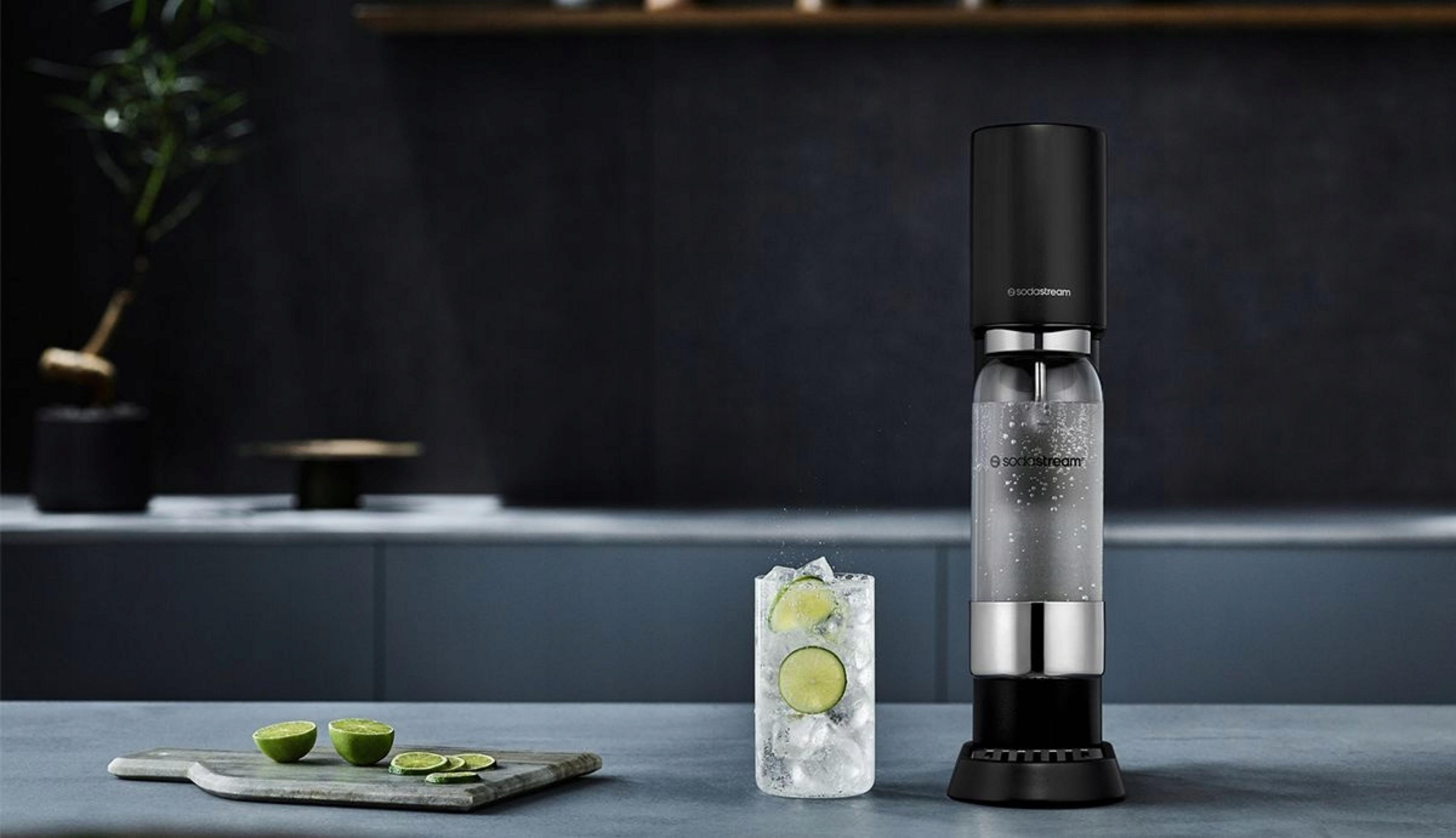 Ein SodaStream-Gerät steht neben einem Glas mit Eis und Limettenscheiben.