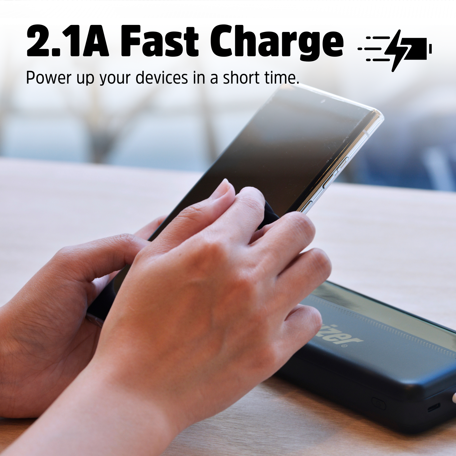 Handen houden een smartphone boven een powerbank. Tekst: 2.1A snelladen.