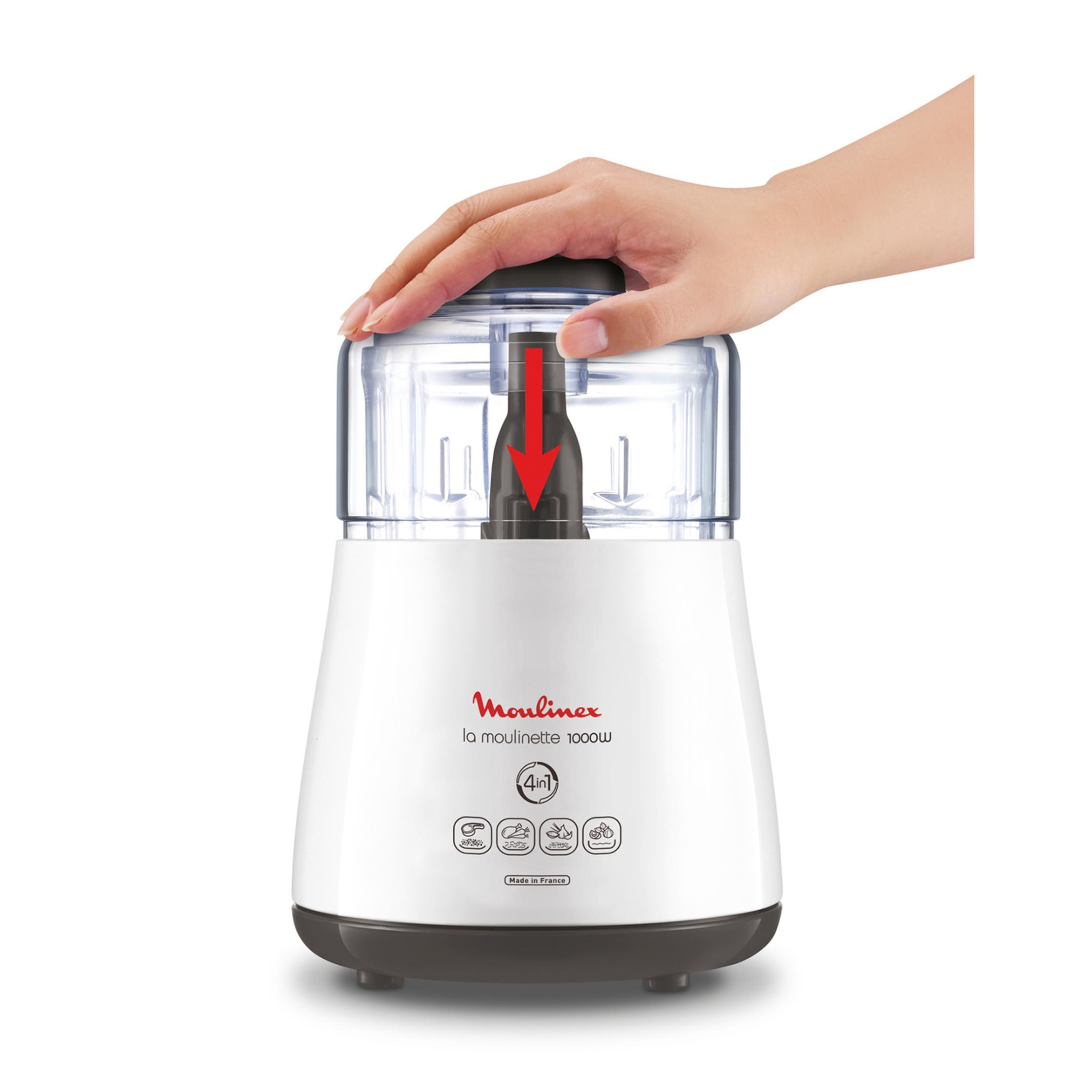 Una mano preme la freccia rossa sul coperchio trasparente di un robot da cucina bianco.