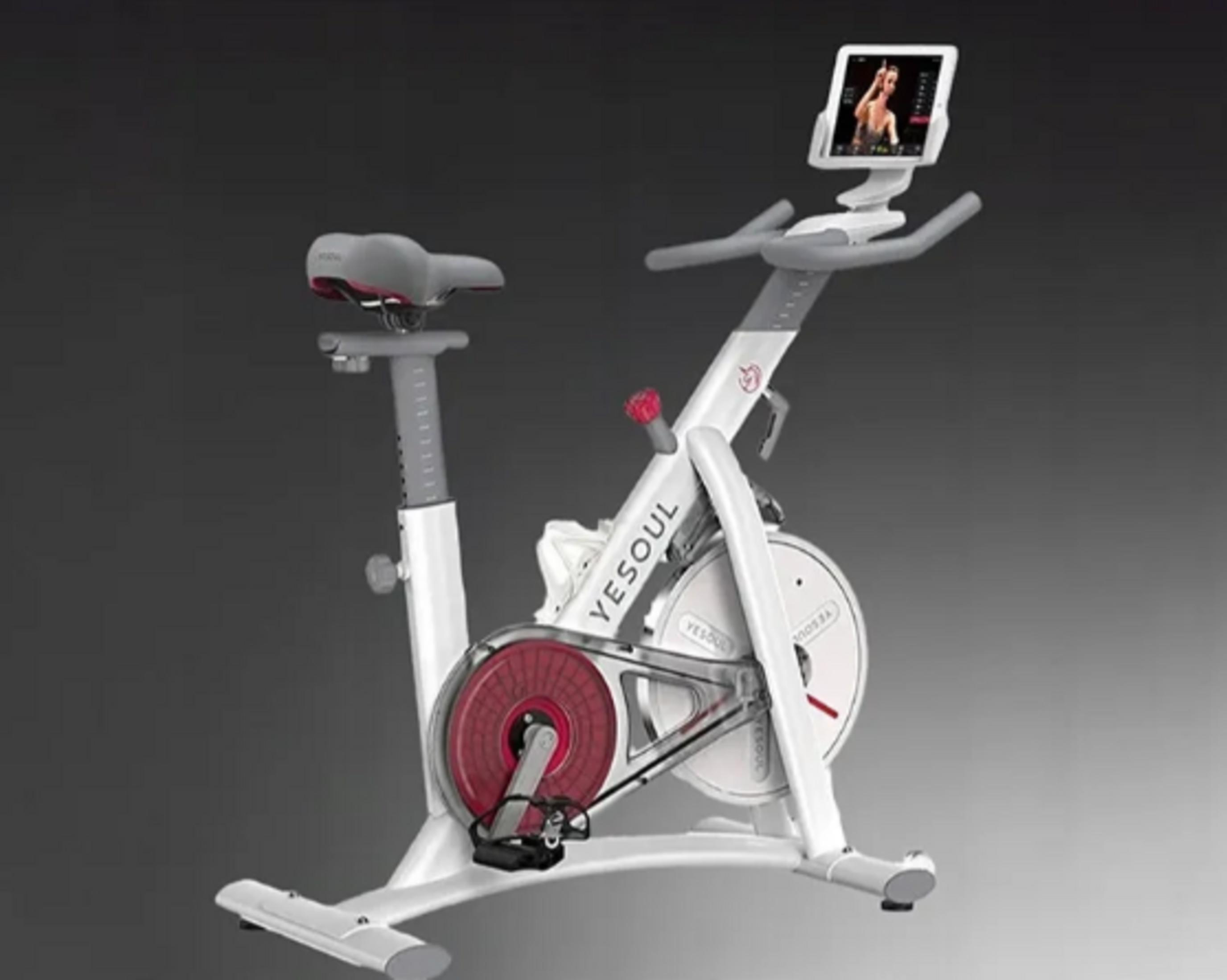 Una cyclette bianca con un tablet che mostra una donna.