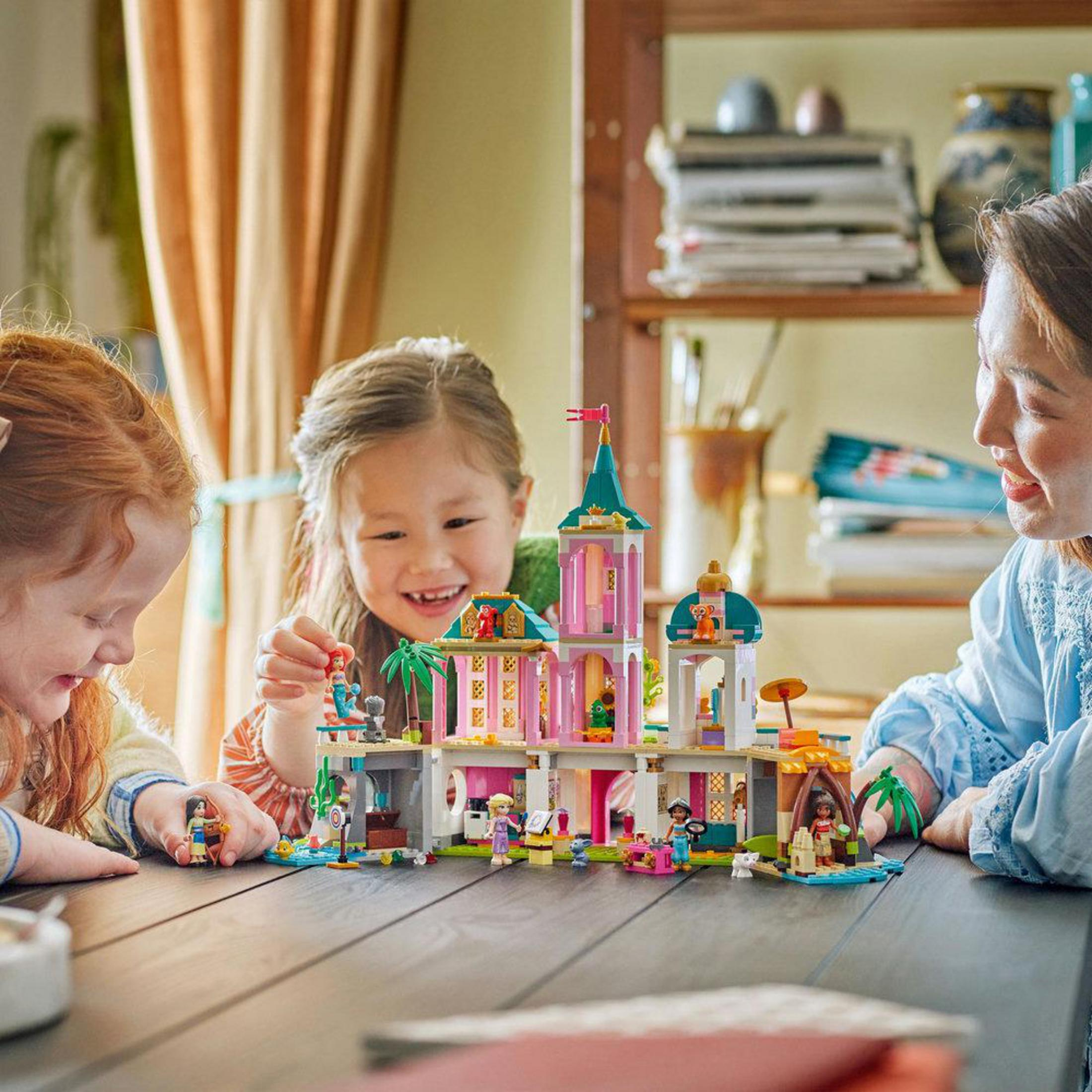 Una familia construye un castillo Lego colorido con figuras. Están sentados a una mesa de madera.