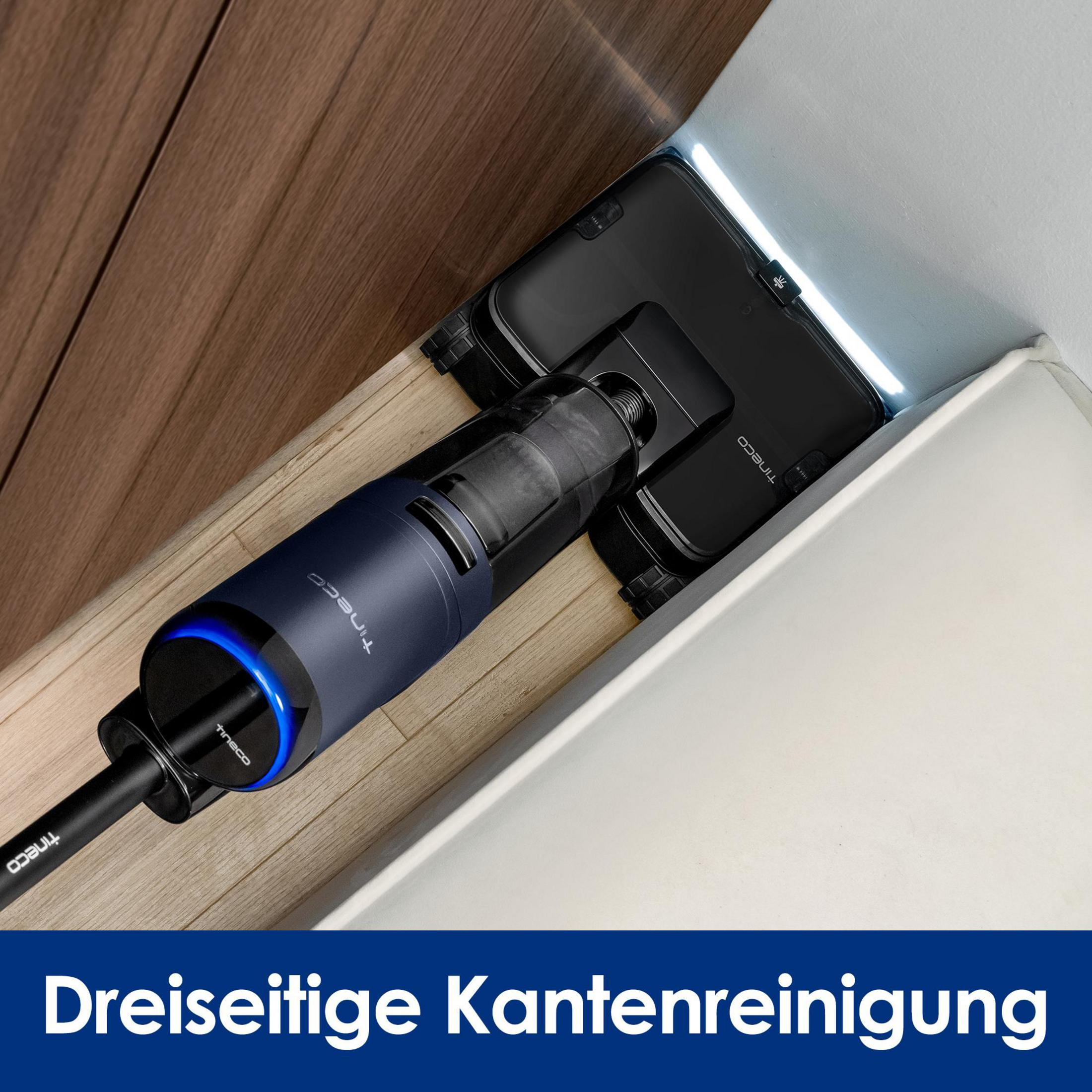 Dunkelblauer Akku-Staubsauger reinigt Ecke auf Holzboden.