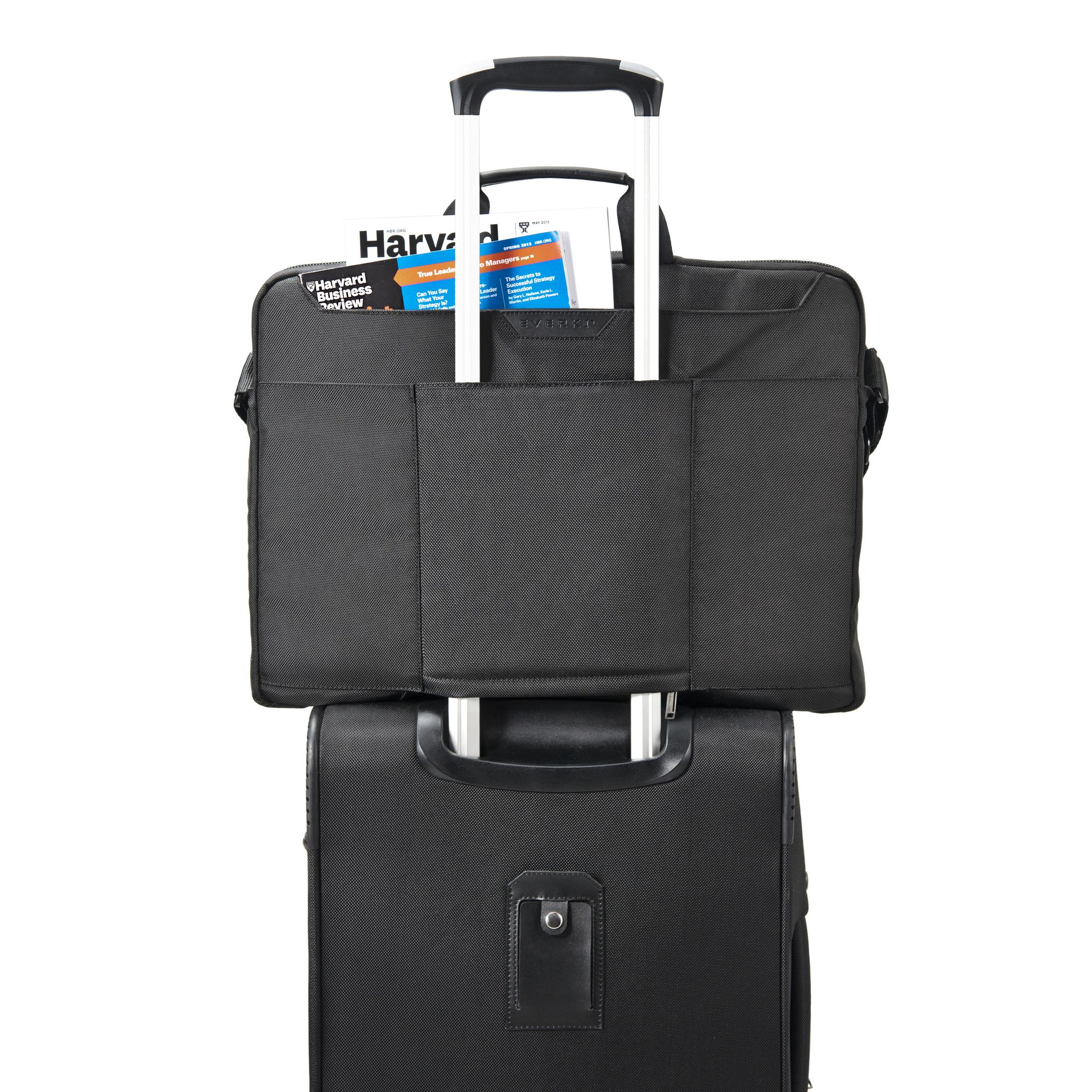 Schwarze Laptoptasche auf einem schwarzen Rollkoffer mit Zeitschriften.
